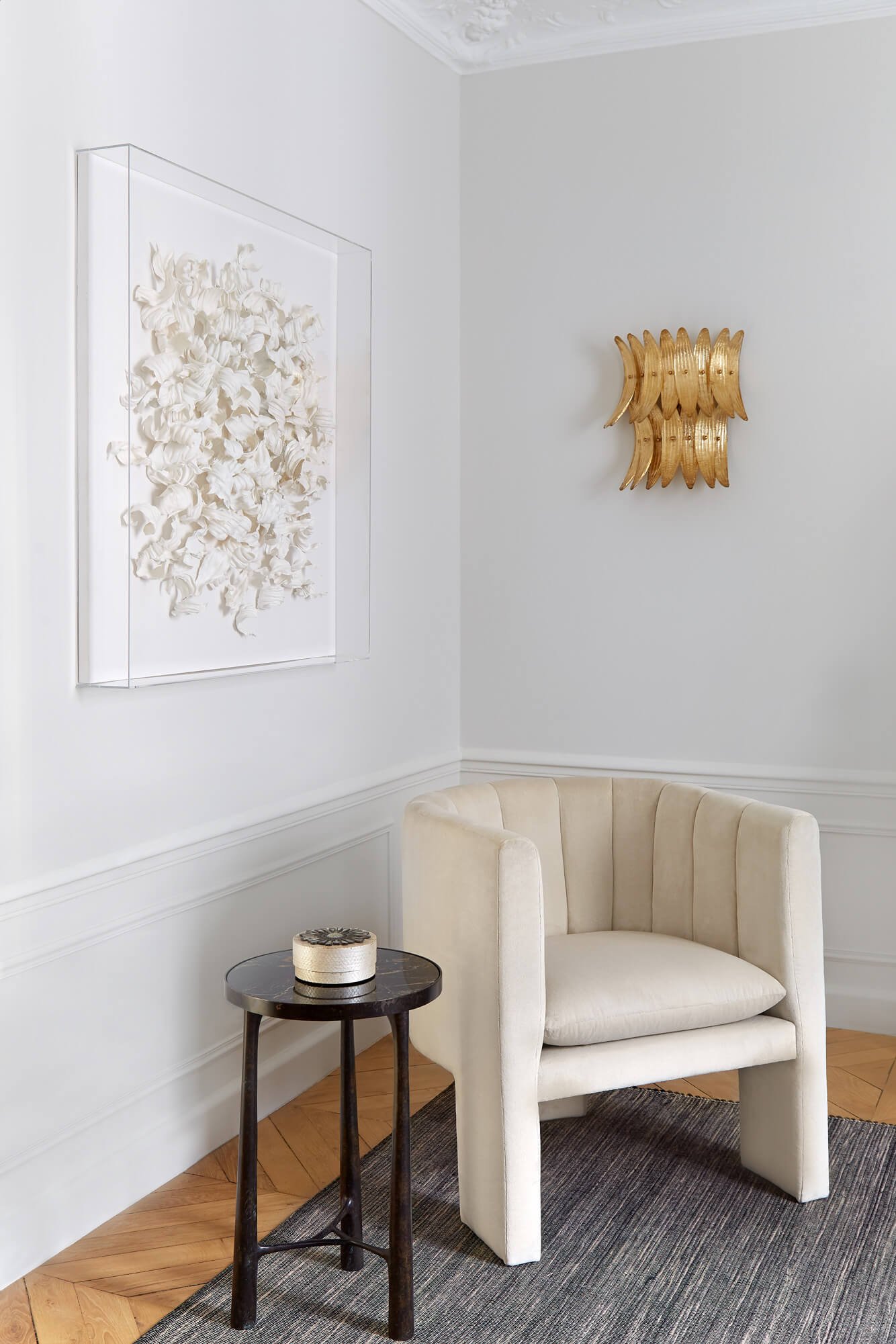  This white velvet chair makes this corner effortlessly sophisticated and modern. The walls feature a chic artwork and golden ornament. 