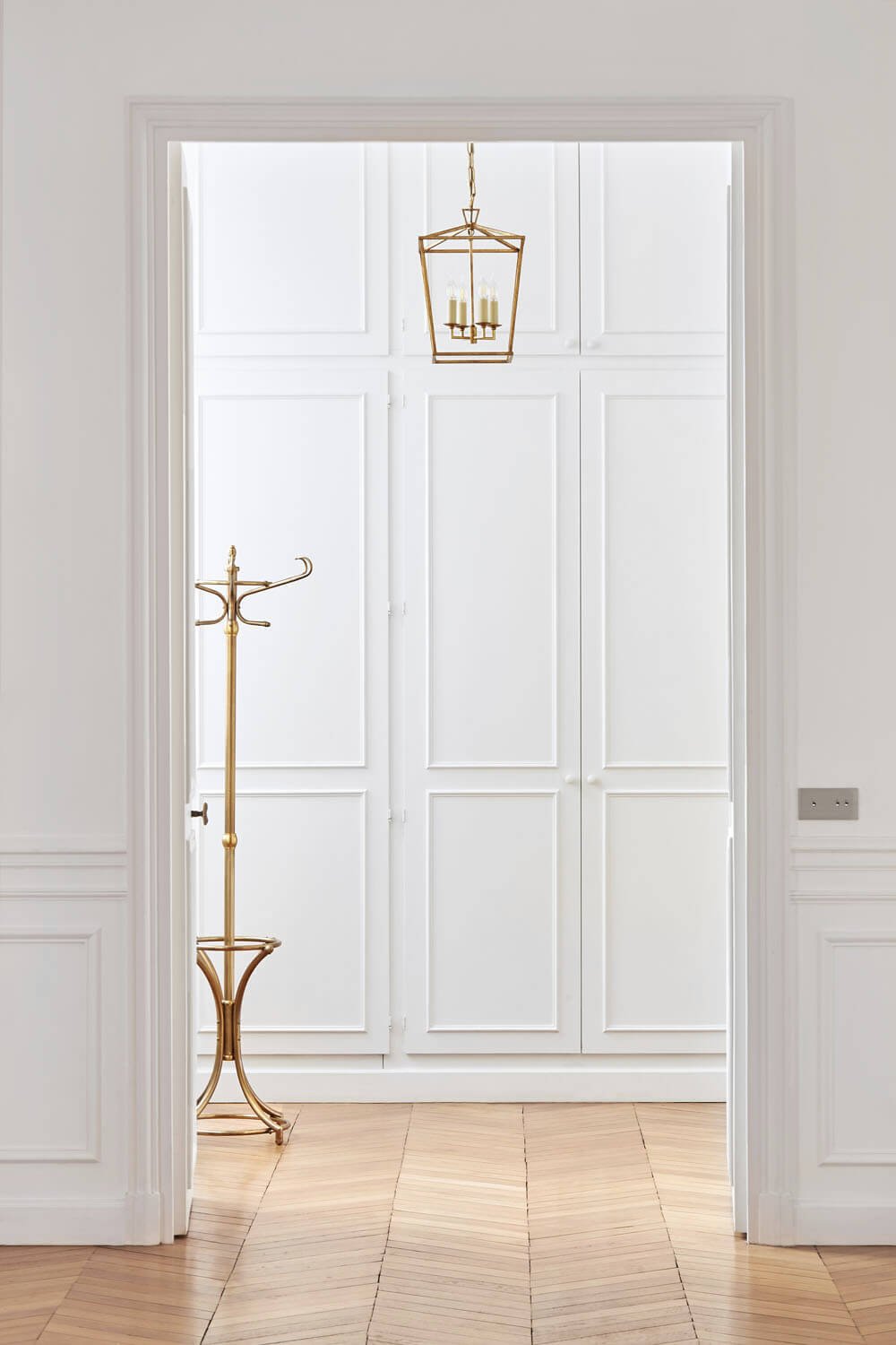  Trocadero apartment with white walls, white door and decorative light fixtures. 