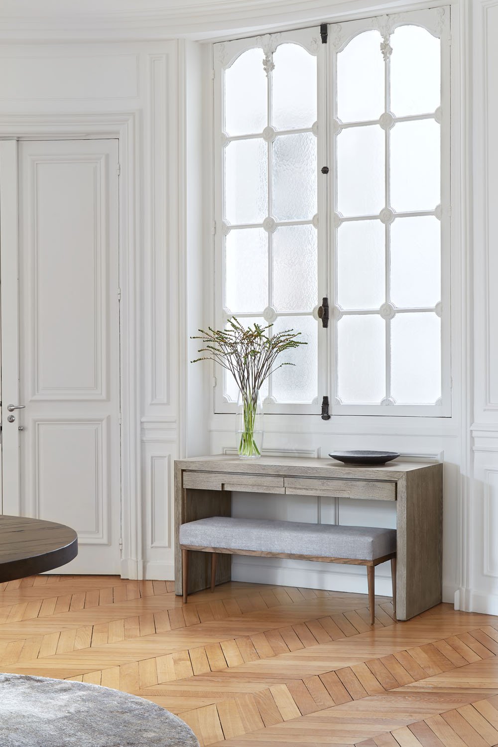  Parisian apartment with white walls, large glass windows and statement table. 