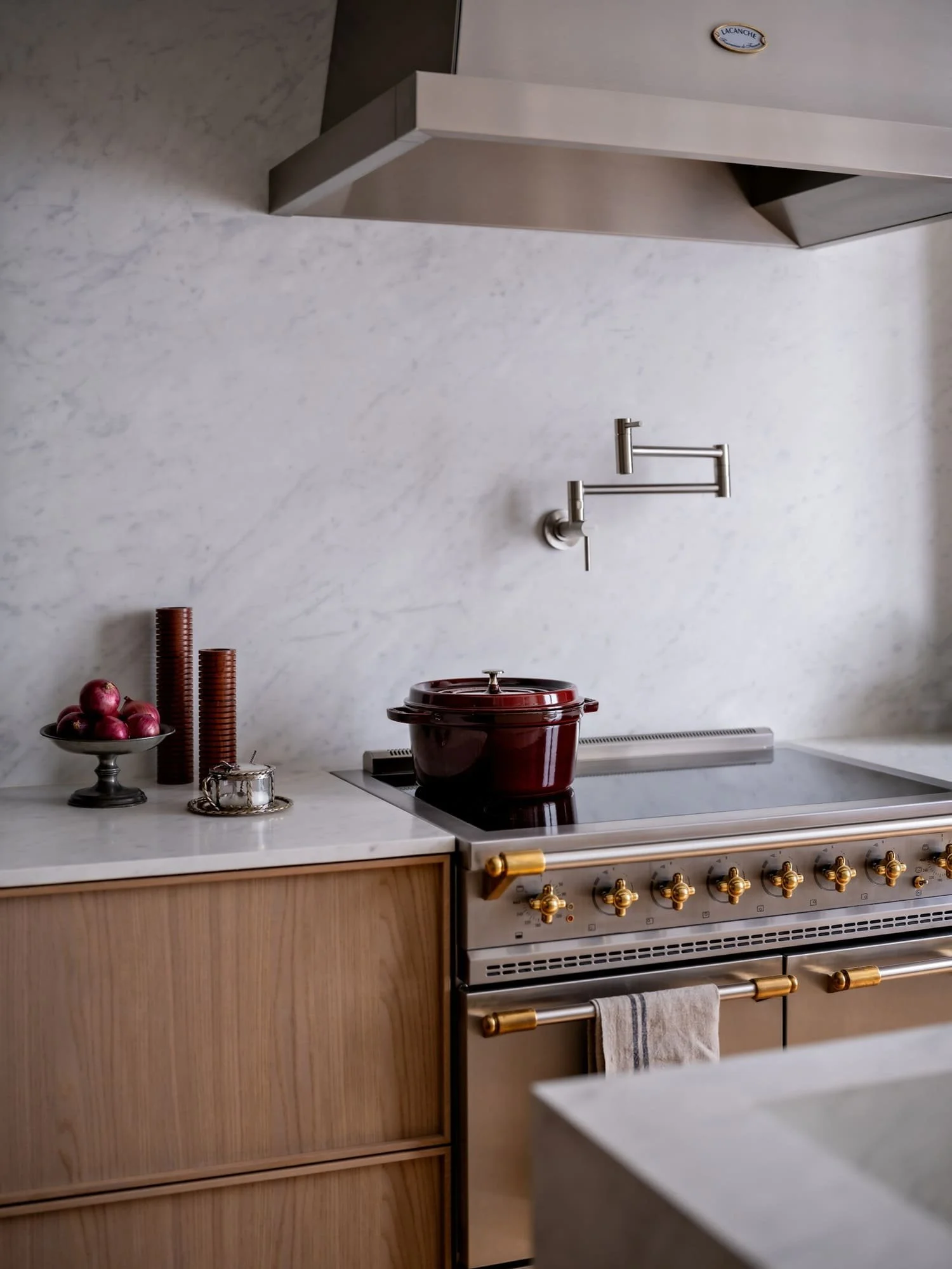 Paris apartment kitchen renovation with Lacanche range cooker, marble backsplash, oak cabinetry and cast iron pot on induction hob
