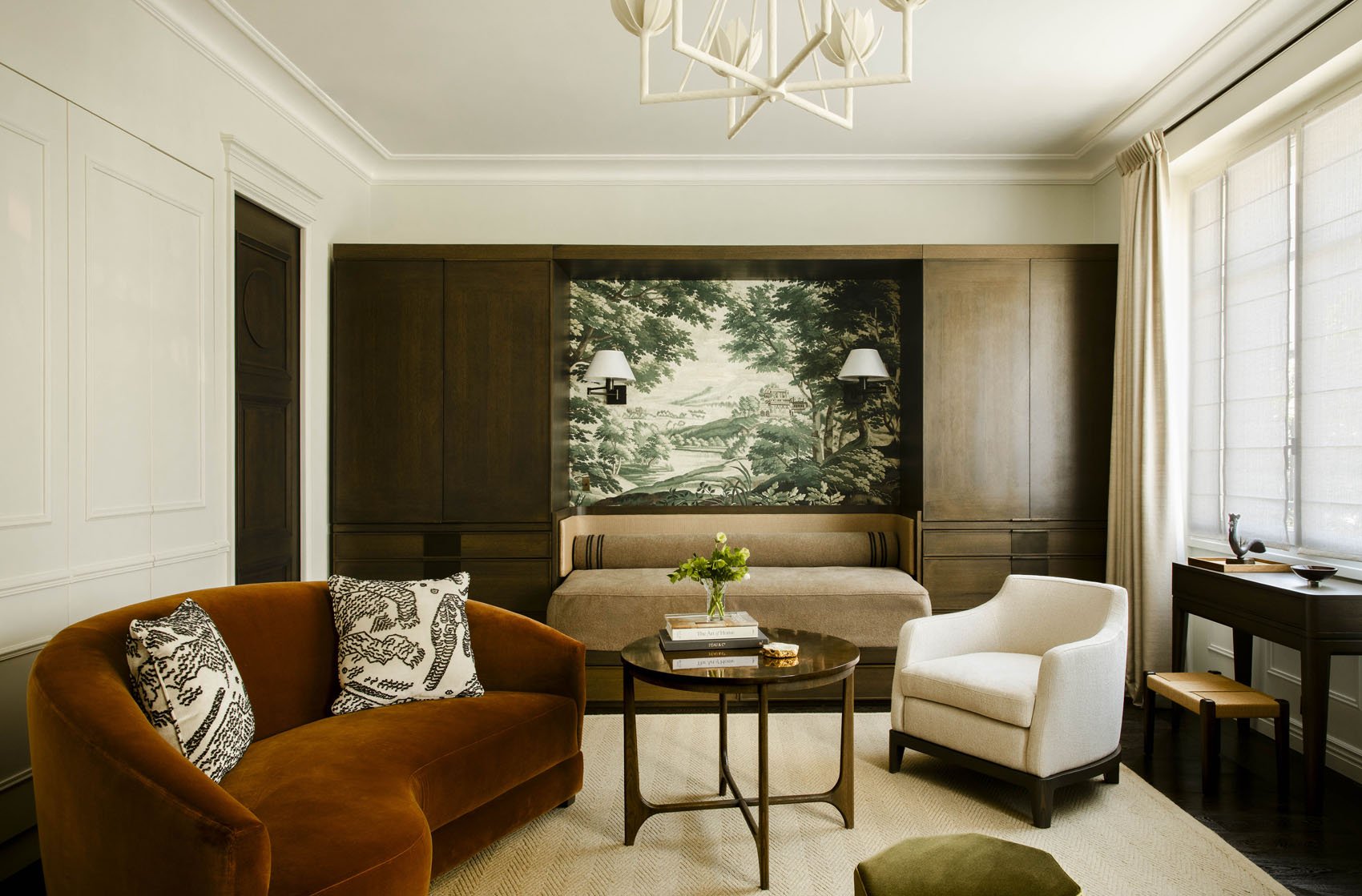 Parisian living room with dark wood panelling, rust velvet sofa, marble coffee table and forest landscape artwork