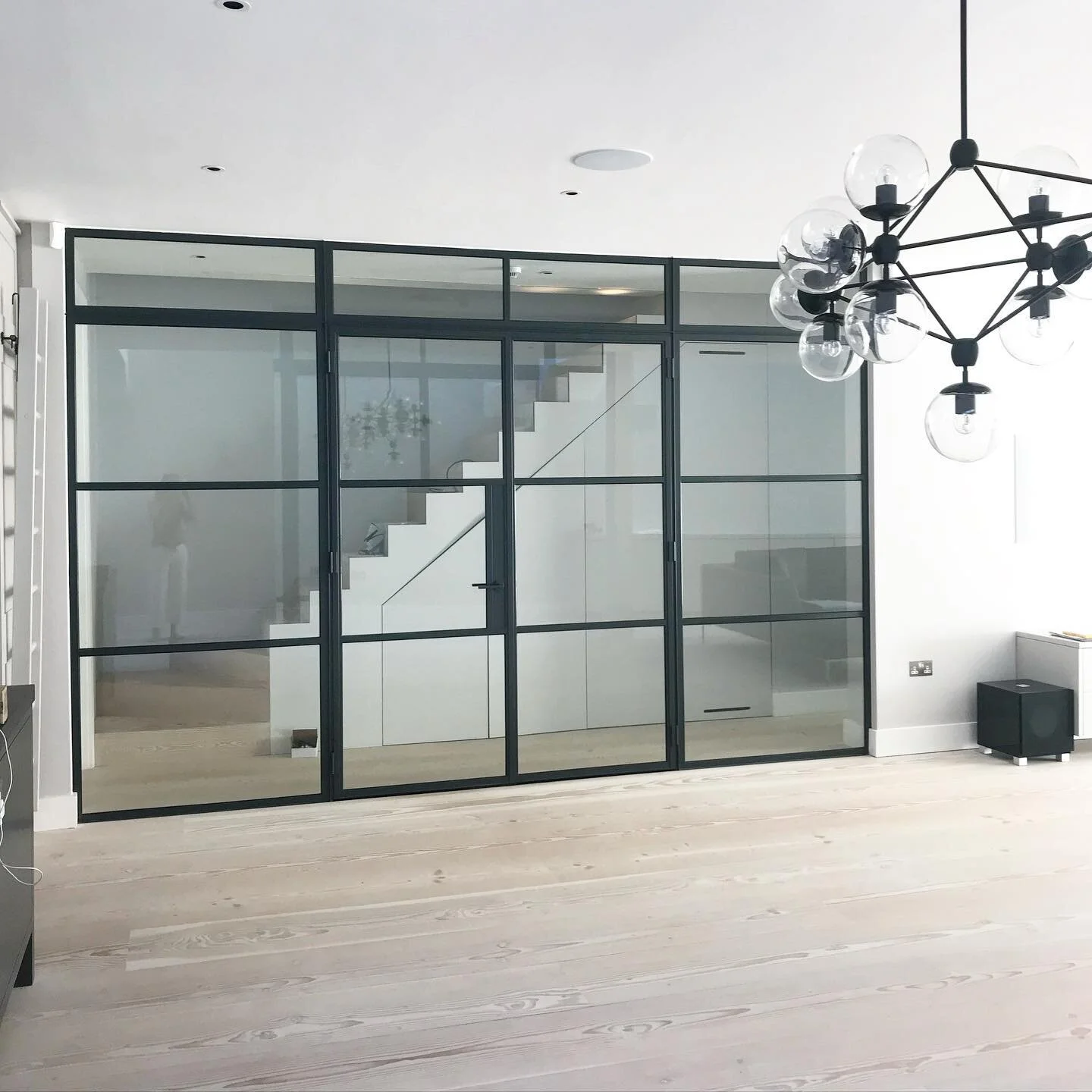 Crittall wall and beautiful lighting in this kitchen family room #interiordesign #interiorarchitecture @dinesen  #floors #dinesen  #kitchen #familyroom #staircase #lighting #pendant