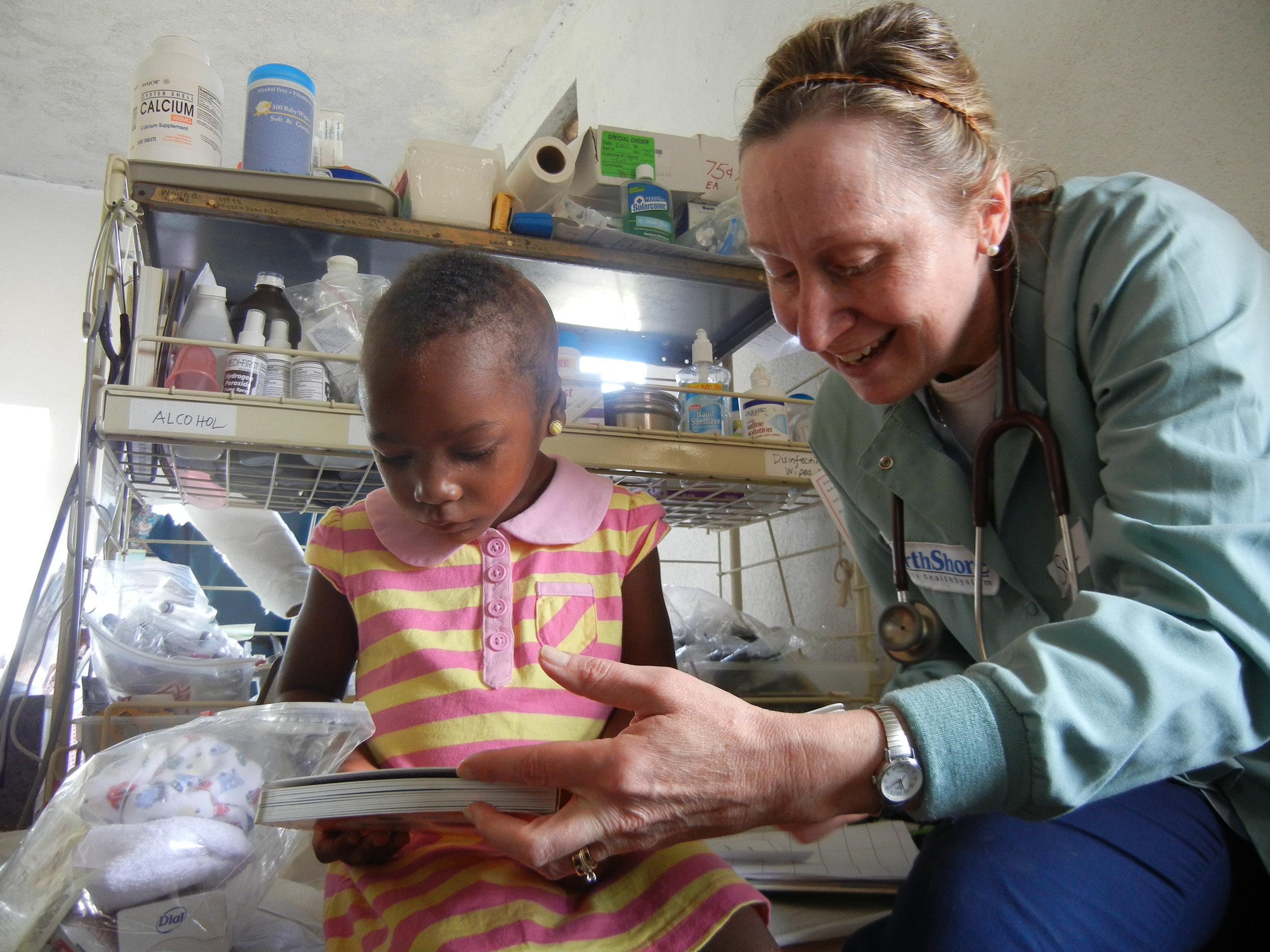 Sue Walsh reads to a Haitian girl displaying severe burn marks from a previous accident. 