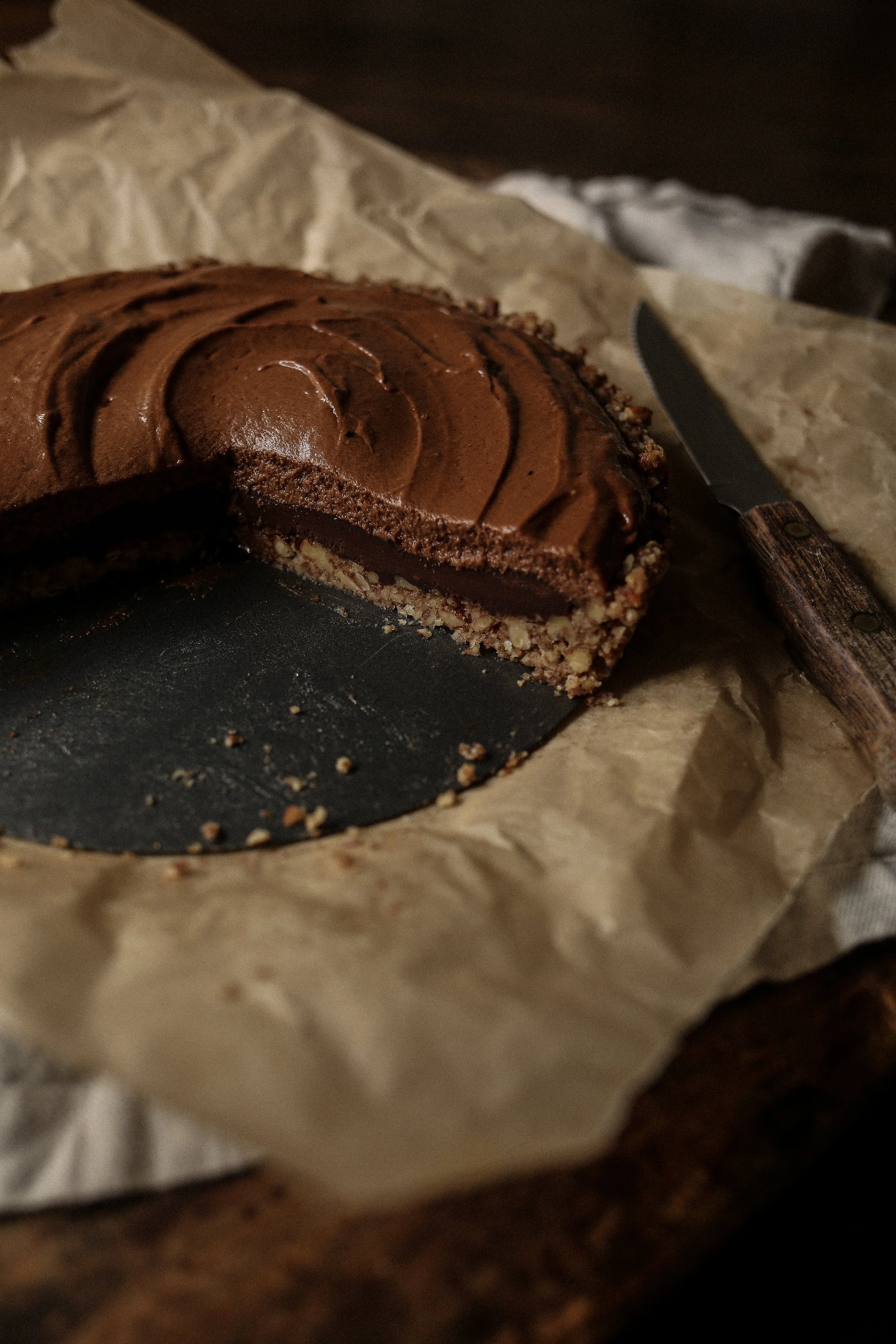 Rich chocolate pecan torte slice showing ganache, mousse, and buttery pecan crust layers