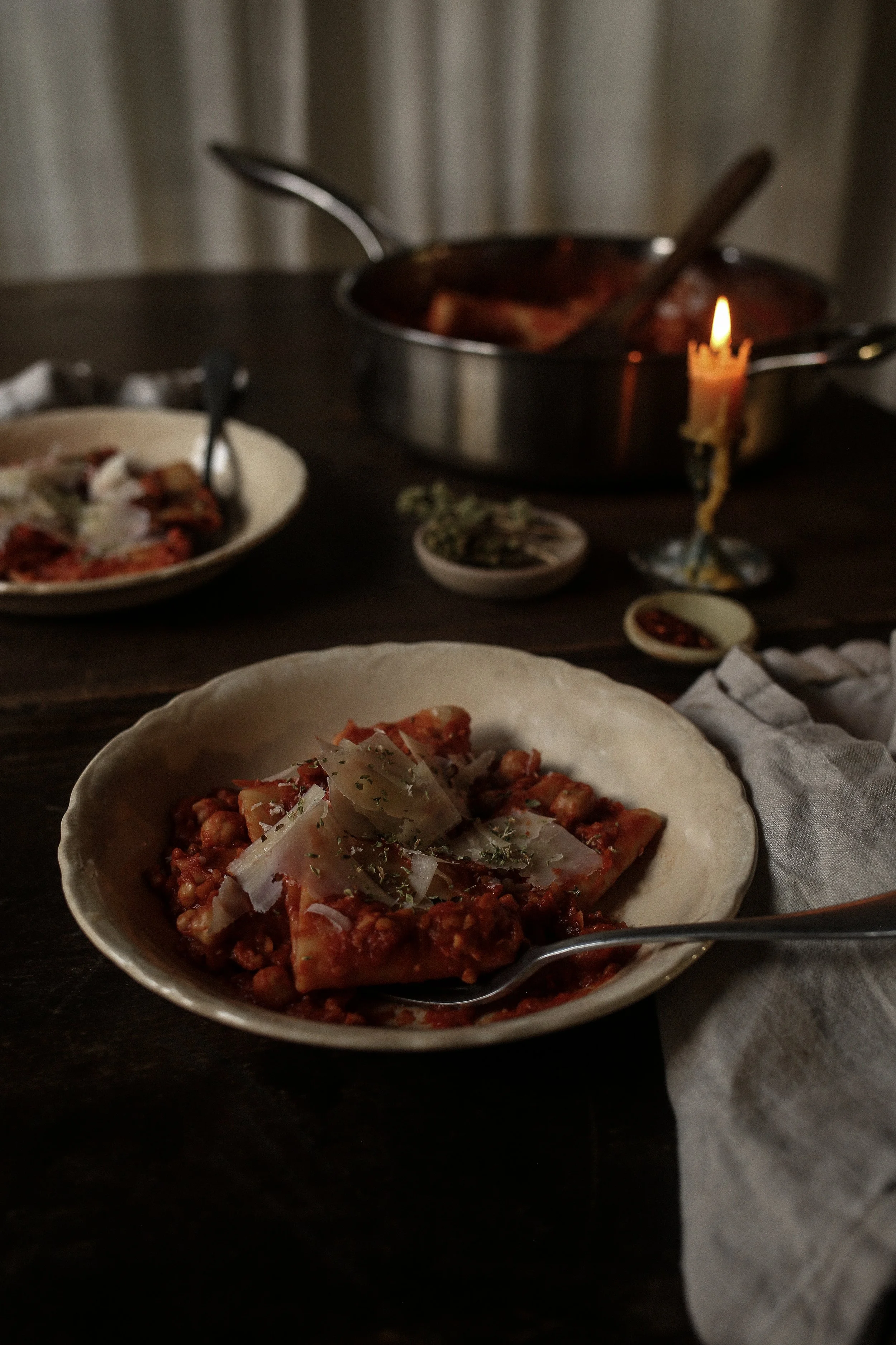 Bowls of pasta with chickpeas topped with oregano and shaved Parmigiano Reggiano
