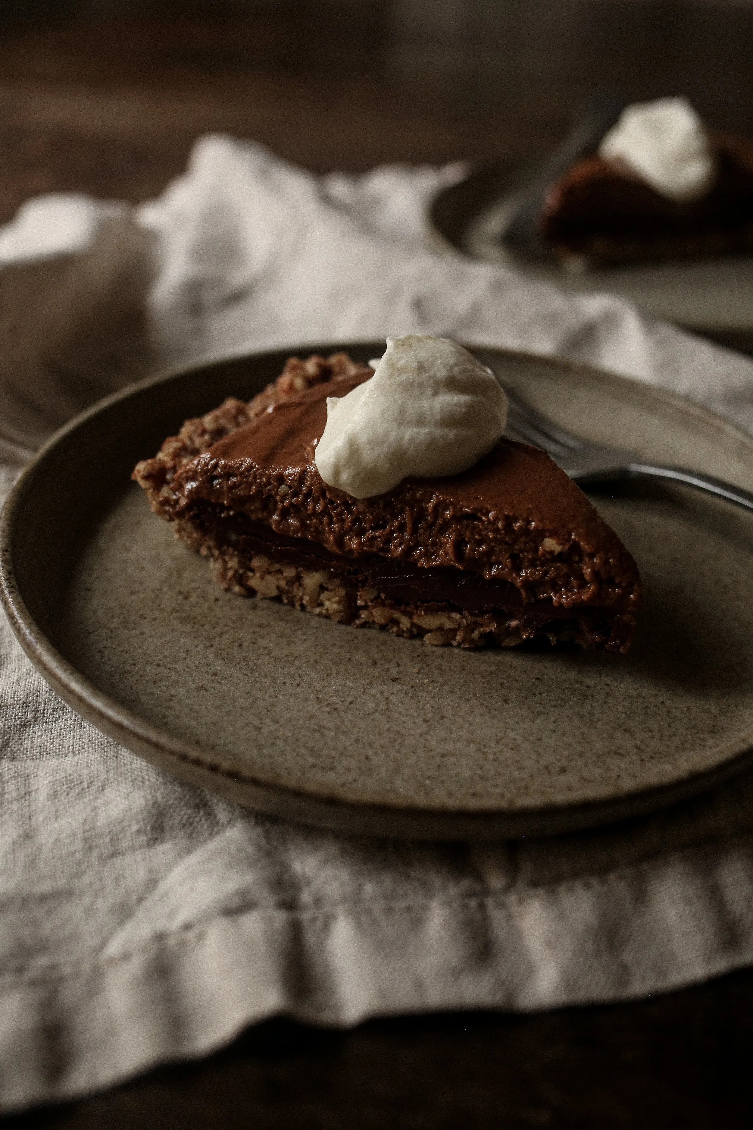 Slice of chocolate pecan torte showing ganache, mousse, and pecan crust layers