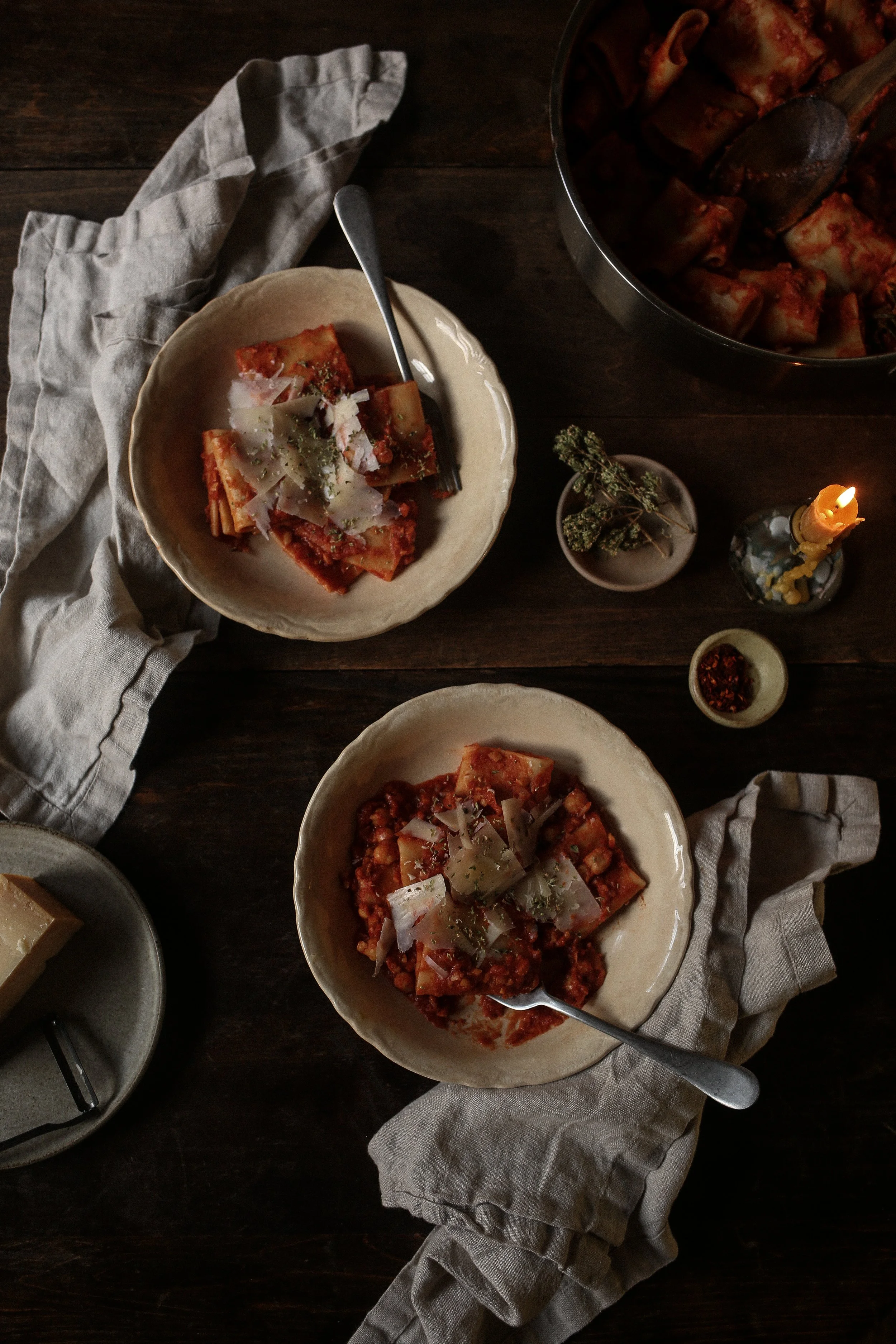 Bowls pasta e ceci served with cheese and oregano on a wood table with tan linens