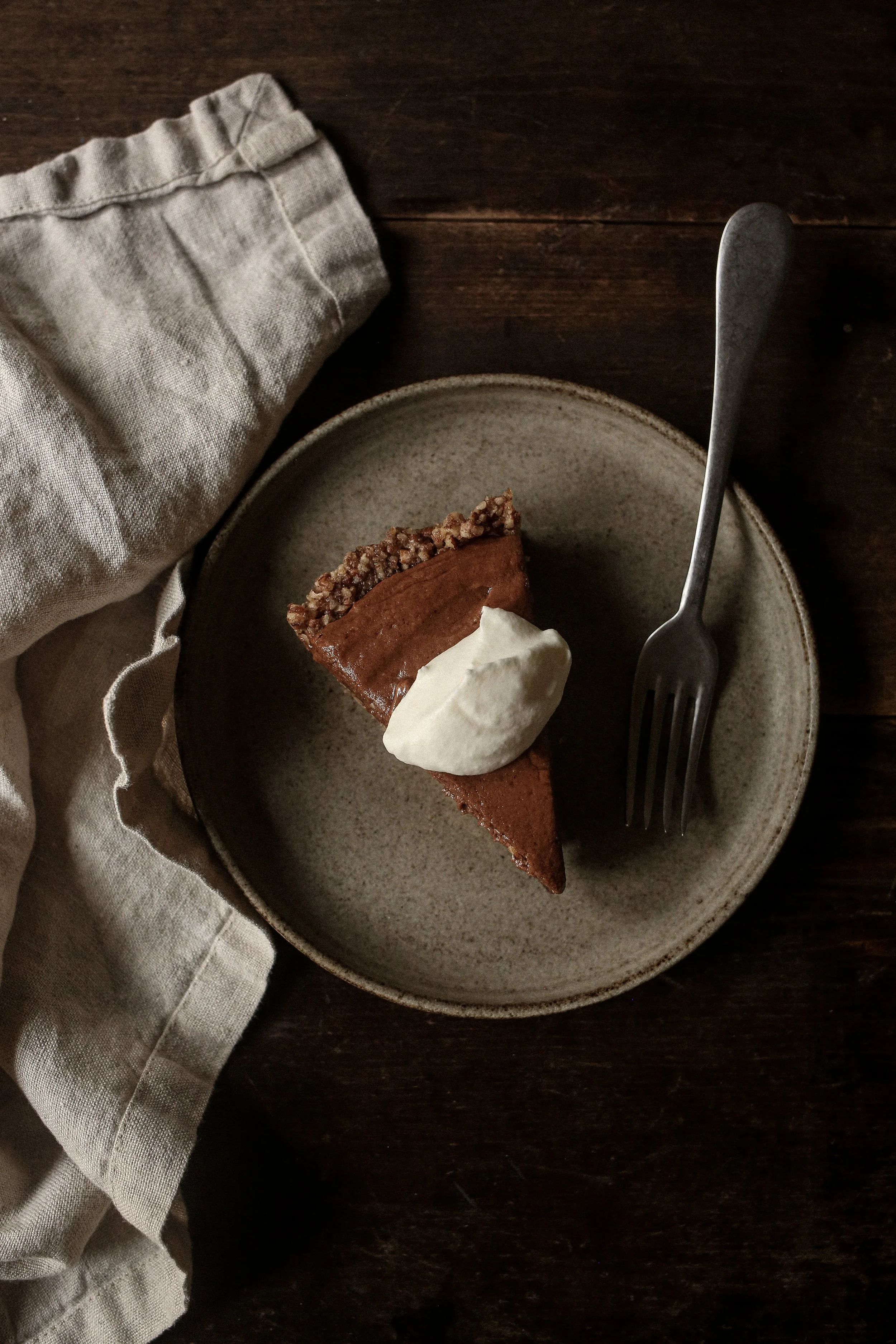 Chocolate pecan torte with silky ganache, espresso chocolate mousse, and whipped cream on a serving plate