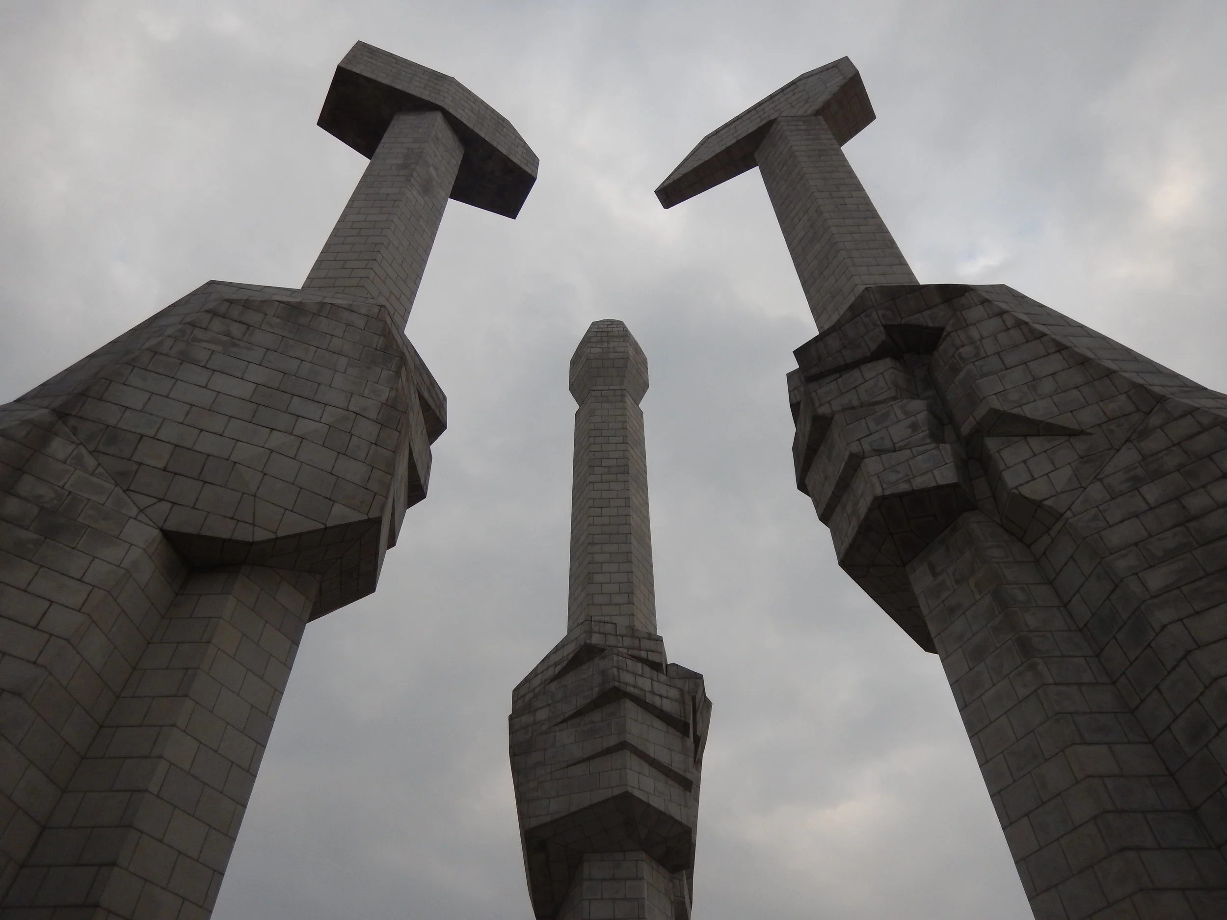 The Monument to the Foundation of the Party features three hands holding a hammer, representing the worker, a sickle, representing the farmer, and a paintbrush, representing the intellectual – these three tools are the official symbols of the ruling Worker's Party of Korea. (Photo by Ethan Jakob Craft.)