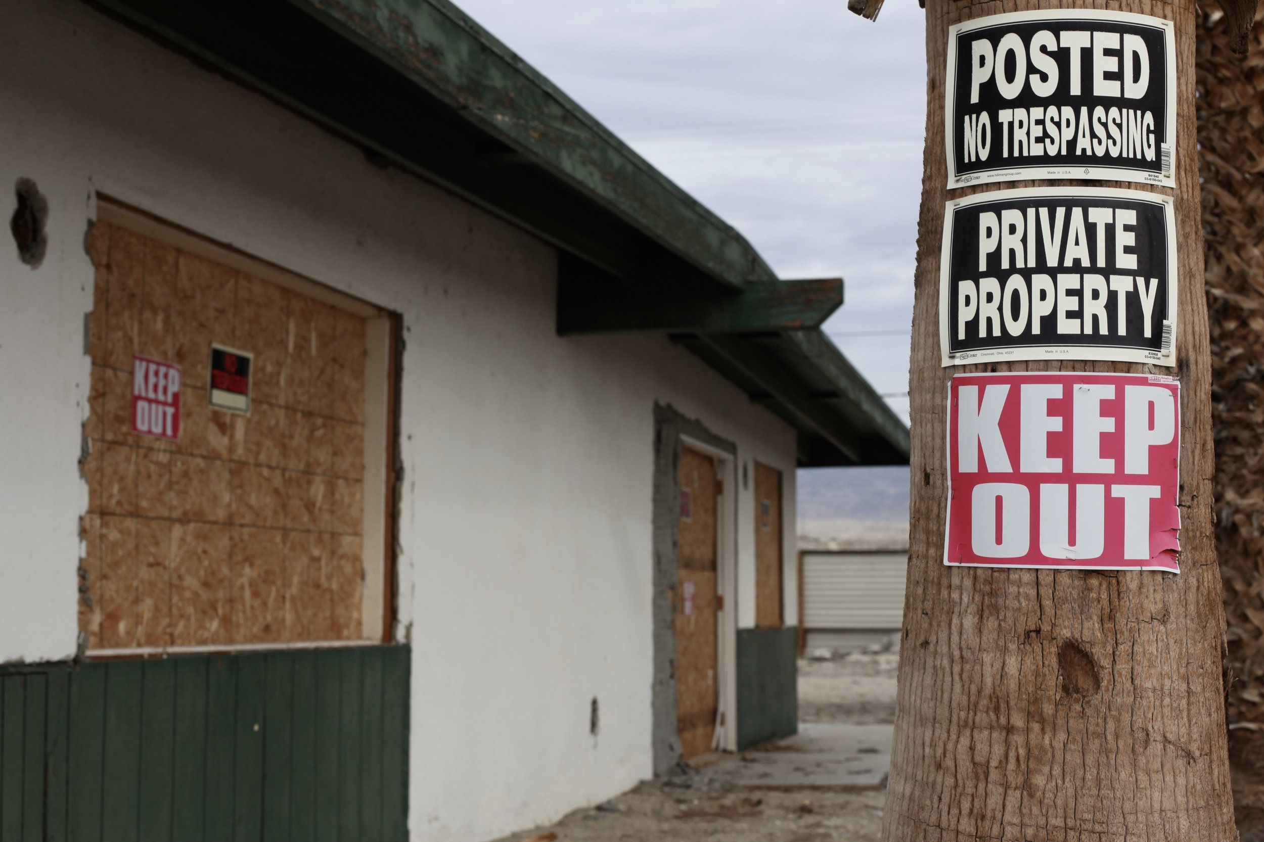 Multiple signs warn trespassers to stay away from an abandoned housing complex in North Shore, Calif. on Jan. 7, 2017. (Photo by Ethan Jakob Craft.)