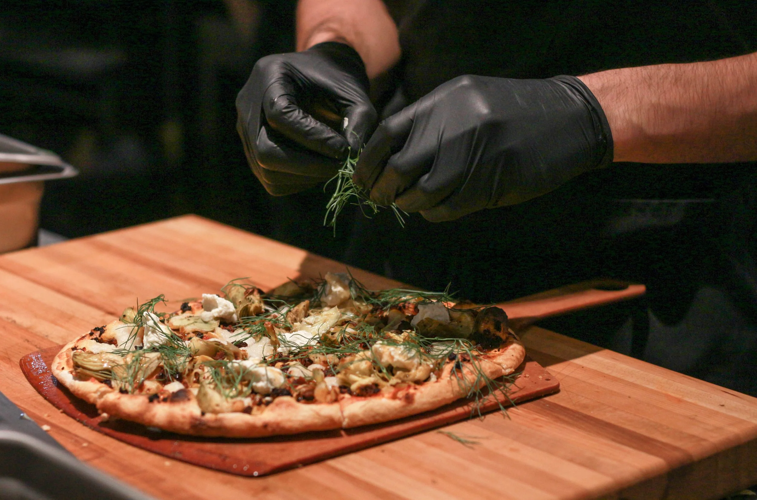 Sous chef Dan Raznavi deftly tops off the Chorizo and Artichoke pizza with a generous helping of fennel fronds. The Chorizo and Artichoke features unique meat and dairy substitutes such as their “soyrizo” bits and cashew mozzarella. (The Unaffiliated Press/Kayla Zhu)