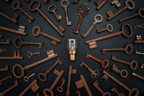 Photo of a lightbulb in the center of a circle of keys all pointing in toward the lightbulb