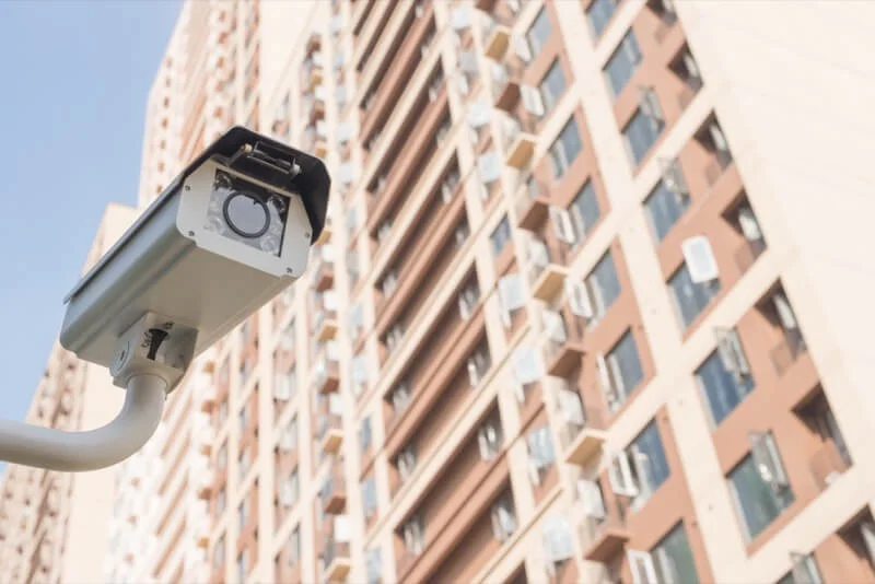 Picture of a surveillance camera with an apartment building in the background