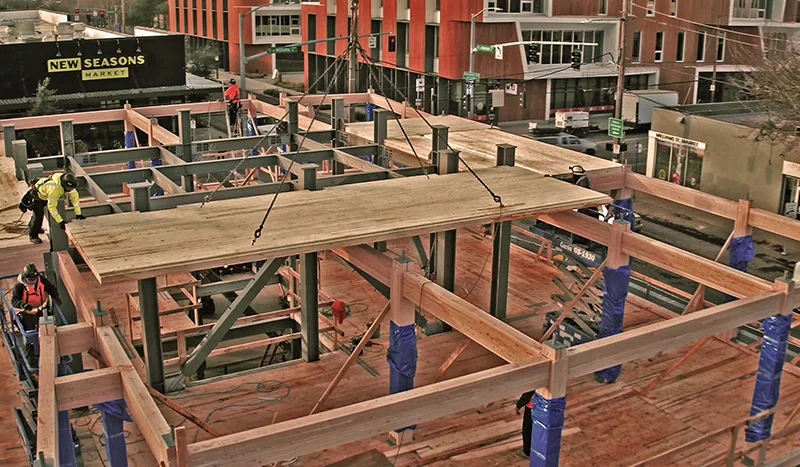 Structural loads are borne by a grid of glulam posts tied to the deep piles onto which CLT panels are lifted and locked into place over steel tubes welded onto heavy steel plates attached to the ends of the columns. (Kaiser Group)