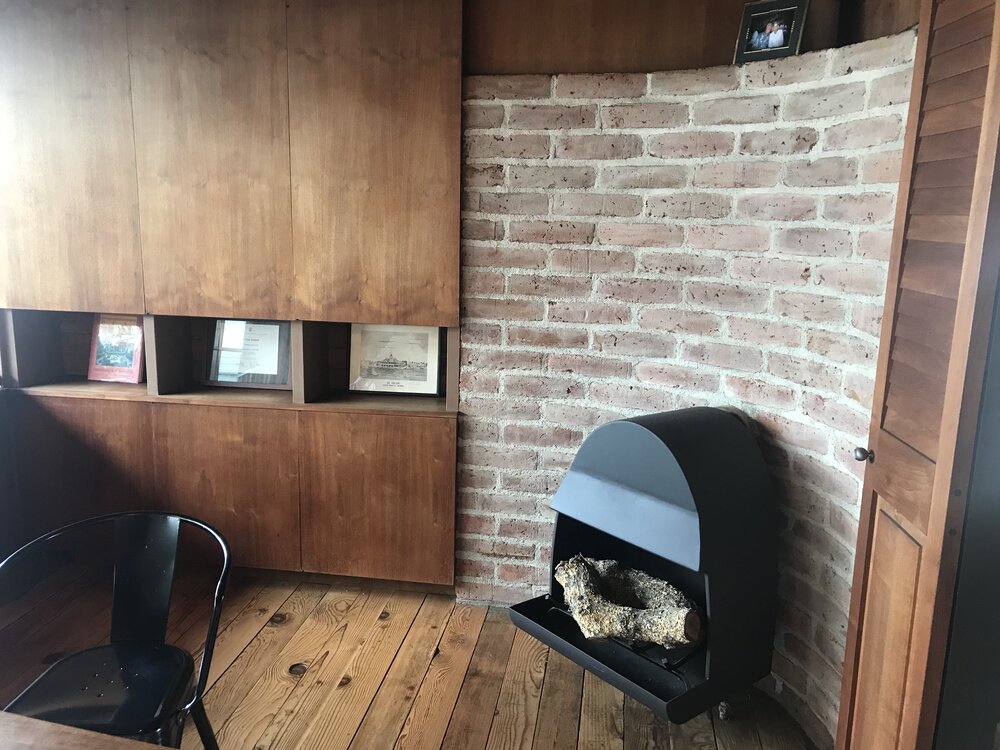 Original cabinetry, fireplace and brick wall in main office