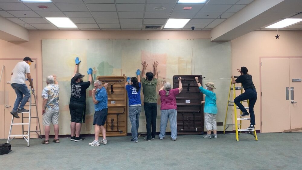 The mural being carefully detached from a wall in the Yorba Linda library community room.