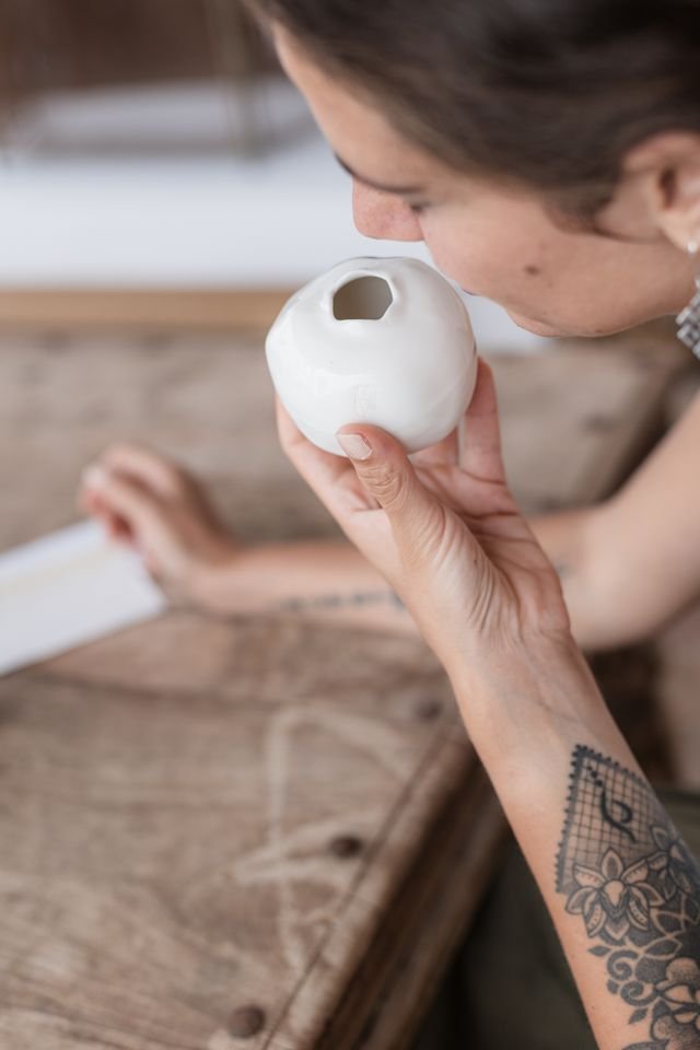 A woman breathing in scent from a handmade white ceramic inhalation pomegranate, made by a local Algarve potter for La-Eva's scent rituals at Casa Fuzetta in Olhão.