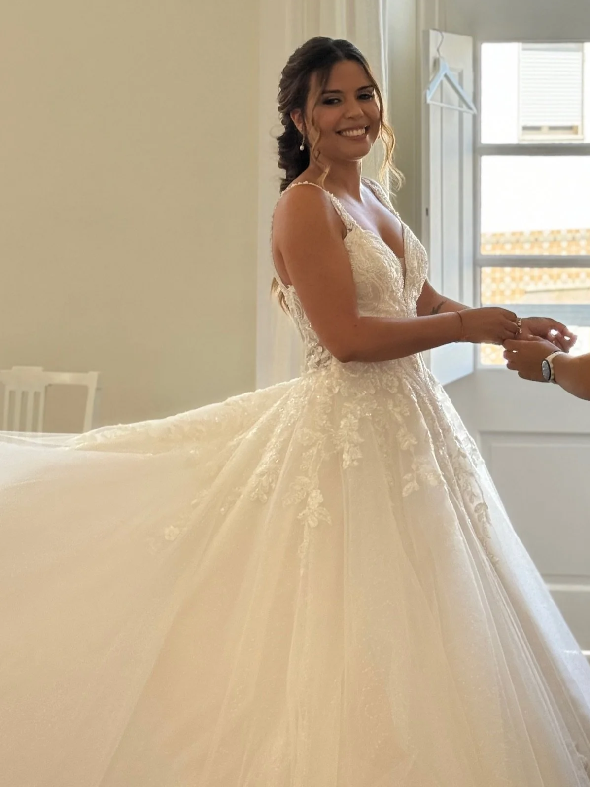 Casa Fuzetta House Manager Claudia on her wedding day, in a white beaded ball gown in a bright bedroom at Casa Fuzetta in Olhão, by tall French doors letting sunlight onto whitewashed walls.