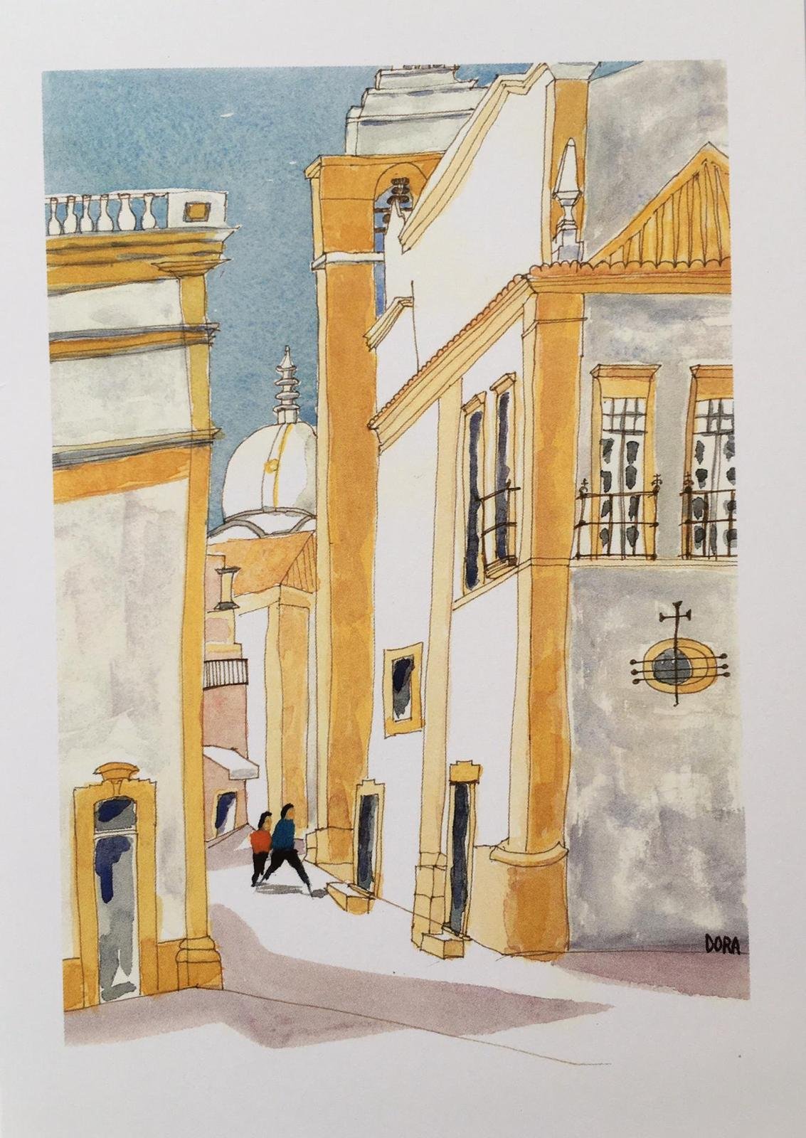 A signed watercolour by Dora Keogh of an Olhao street scene sunlit ochre and white buildings with wrought-iron balconies and a domed church tower, two figures walking through the shadowed lane.