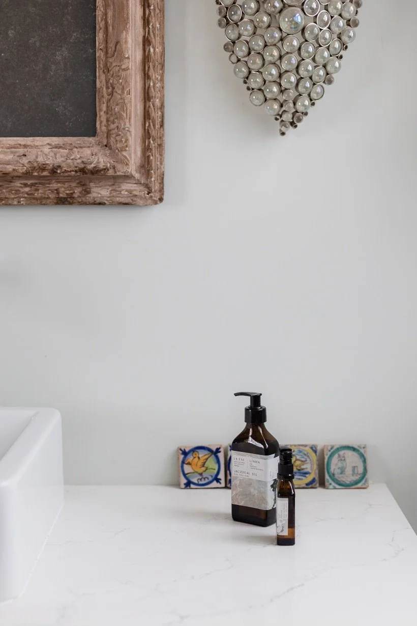La-Eva Linden Universal Oil in 50ml and 200ml amber bottles on a marble washstand, with hand-painted Portuguese tiles and a beaded wall light