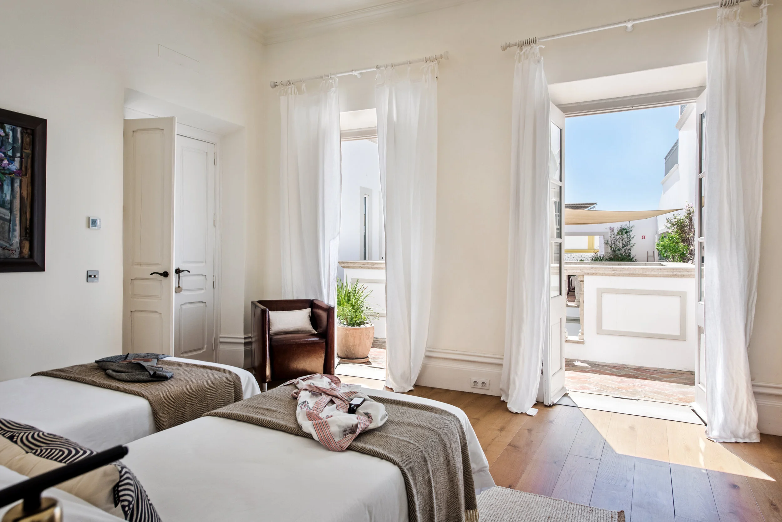 The Dancer Suite at Casa Fuzetta with twin beds, billowing white curtains and French doors opening onto a private terrace.