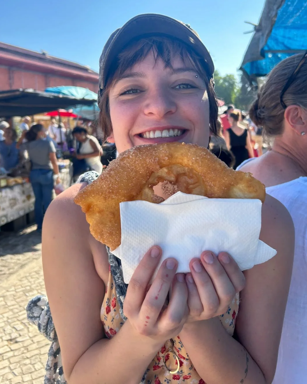 A young visitor smiles at the Saturday market in Olhão, a short walk from Casa Fuzetta, holding up a freshly fried sugared churros (farturas) from one of the street stalls.