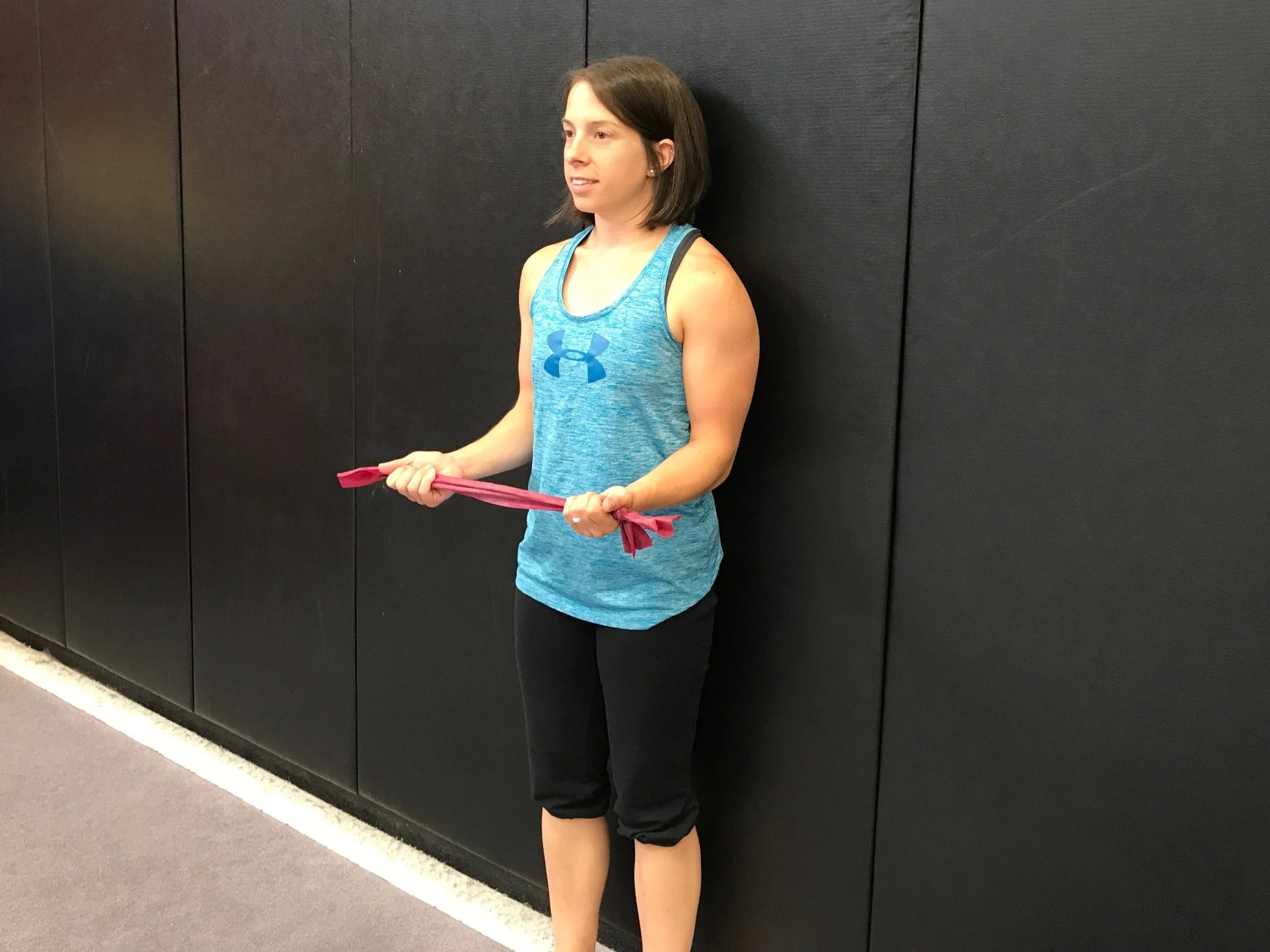 Starting position: Standing against the wall with your back flat, head neutral. Hold the band with palms up, elbows bent to 90 degrees.
