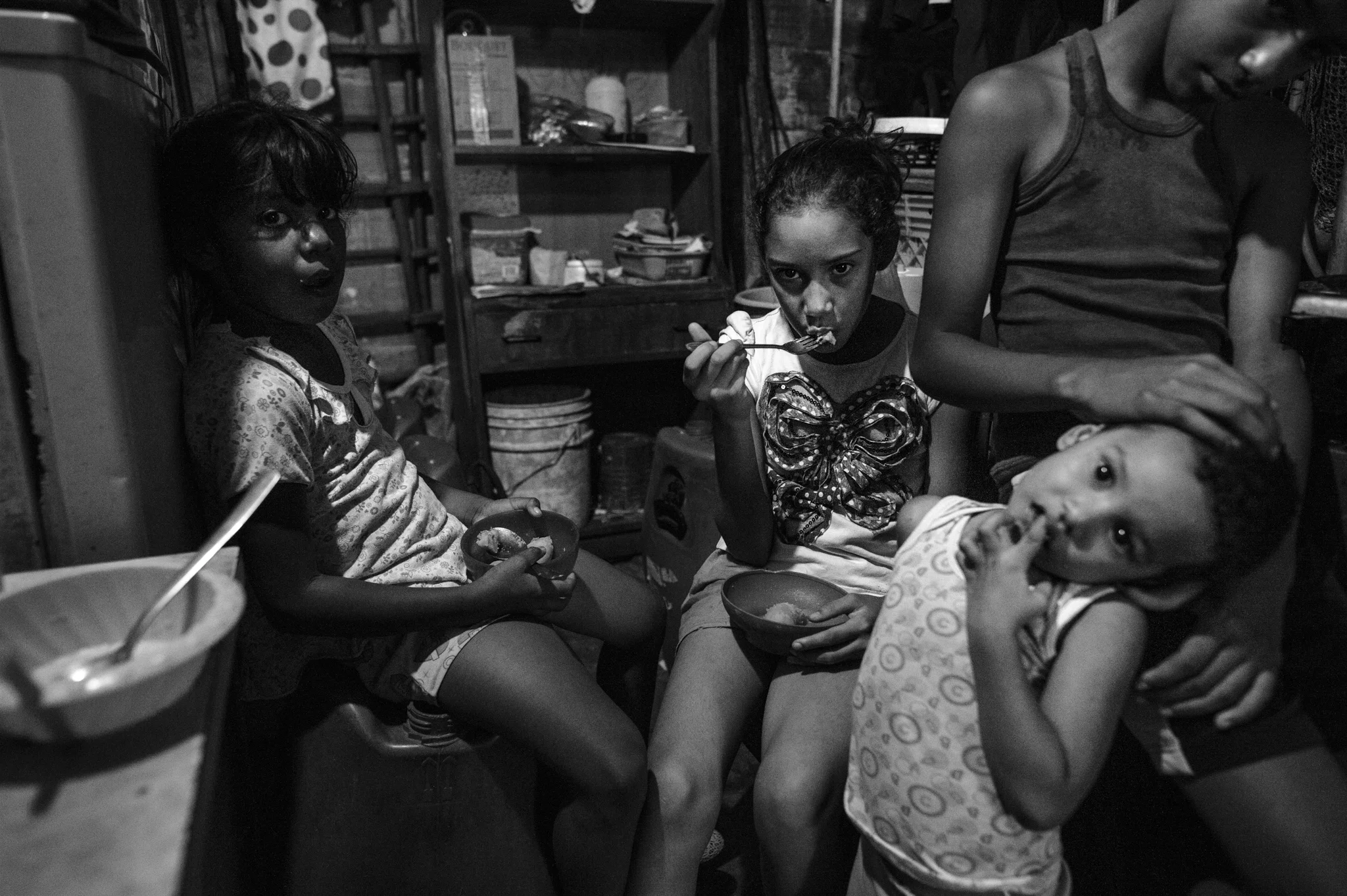  Four siblings eat boiled bananas in the kitchen of their shack in Petare.&nbsp;    