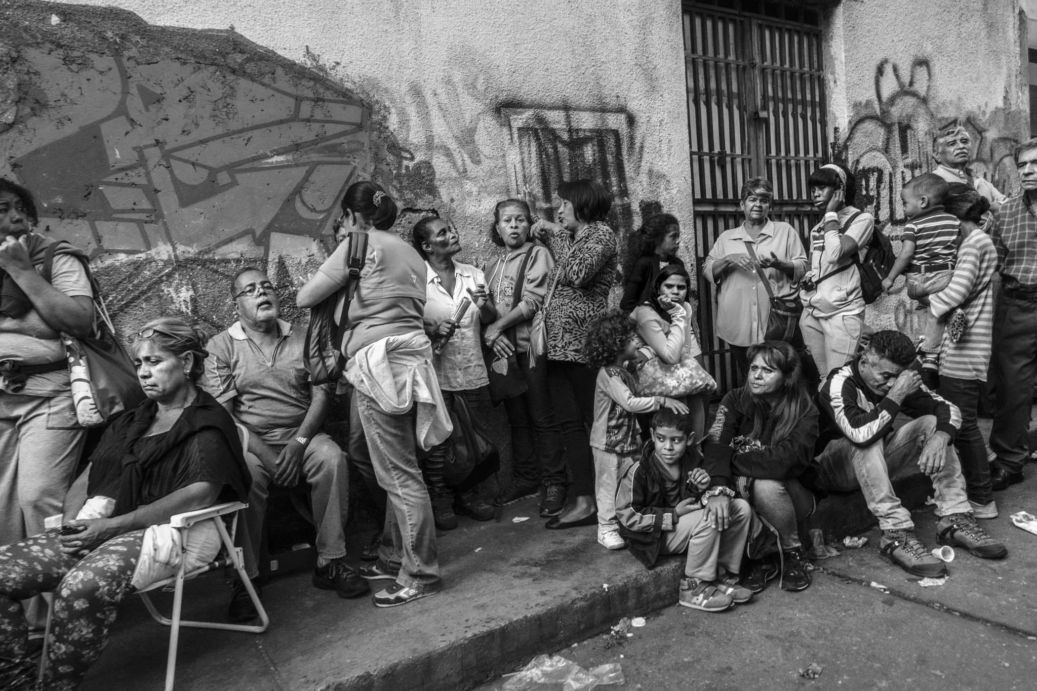 People line up for hours to buy basic products in front of a supermarket in La Candelaria district.