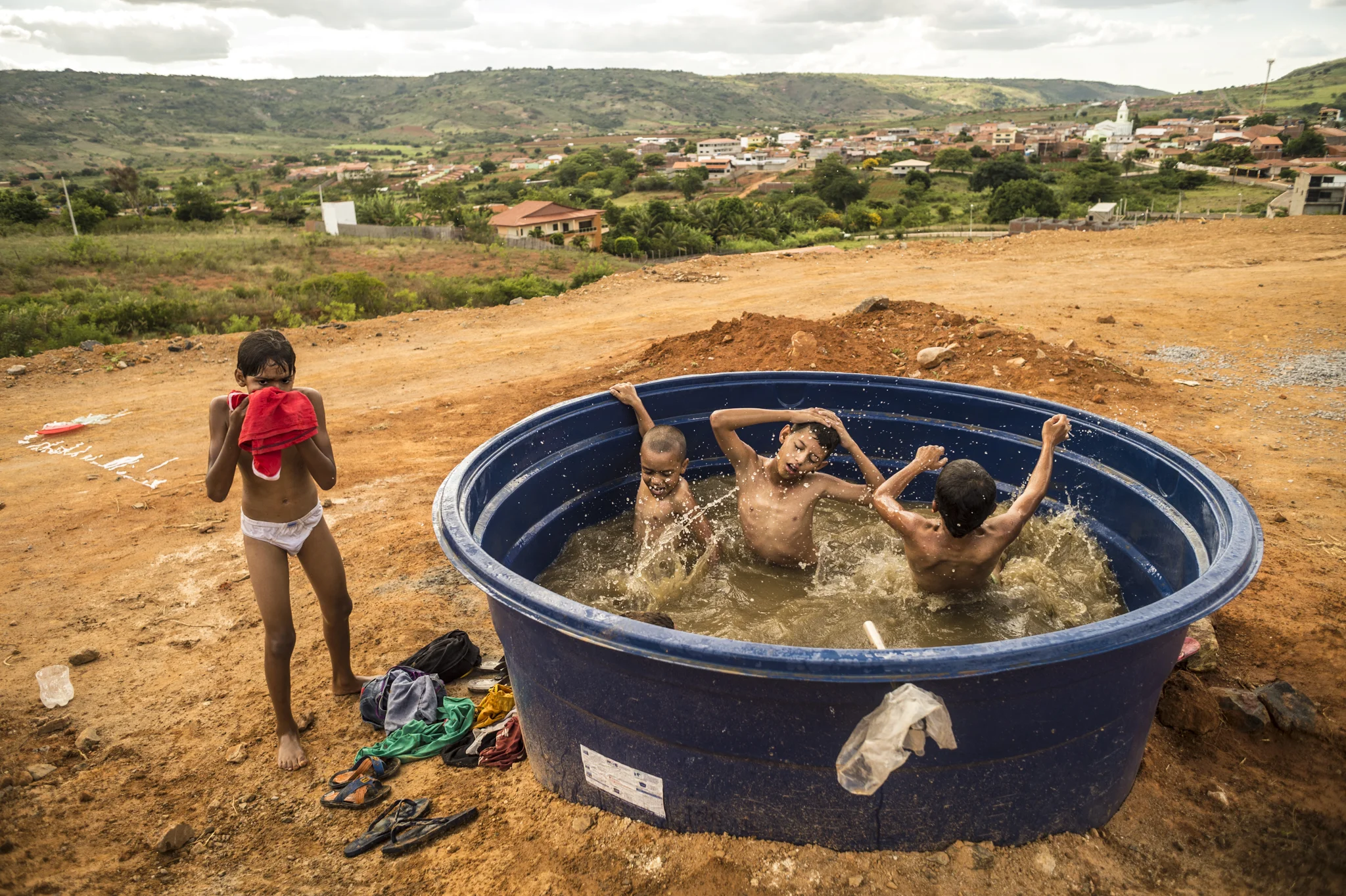 Young sertanejos bathing in a rainwater tank on the edge of a road at the border between Pernambuco and Paraiba. Sertao, a semiarid region of northeast Brazil, is now experiencing the hardest drought of the last 50 years.    