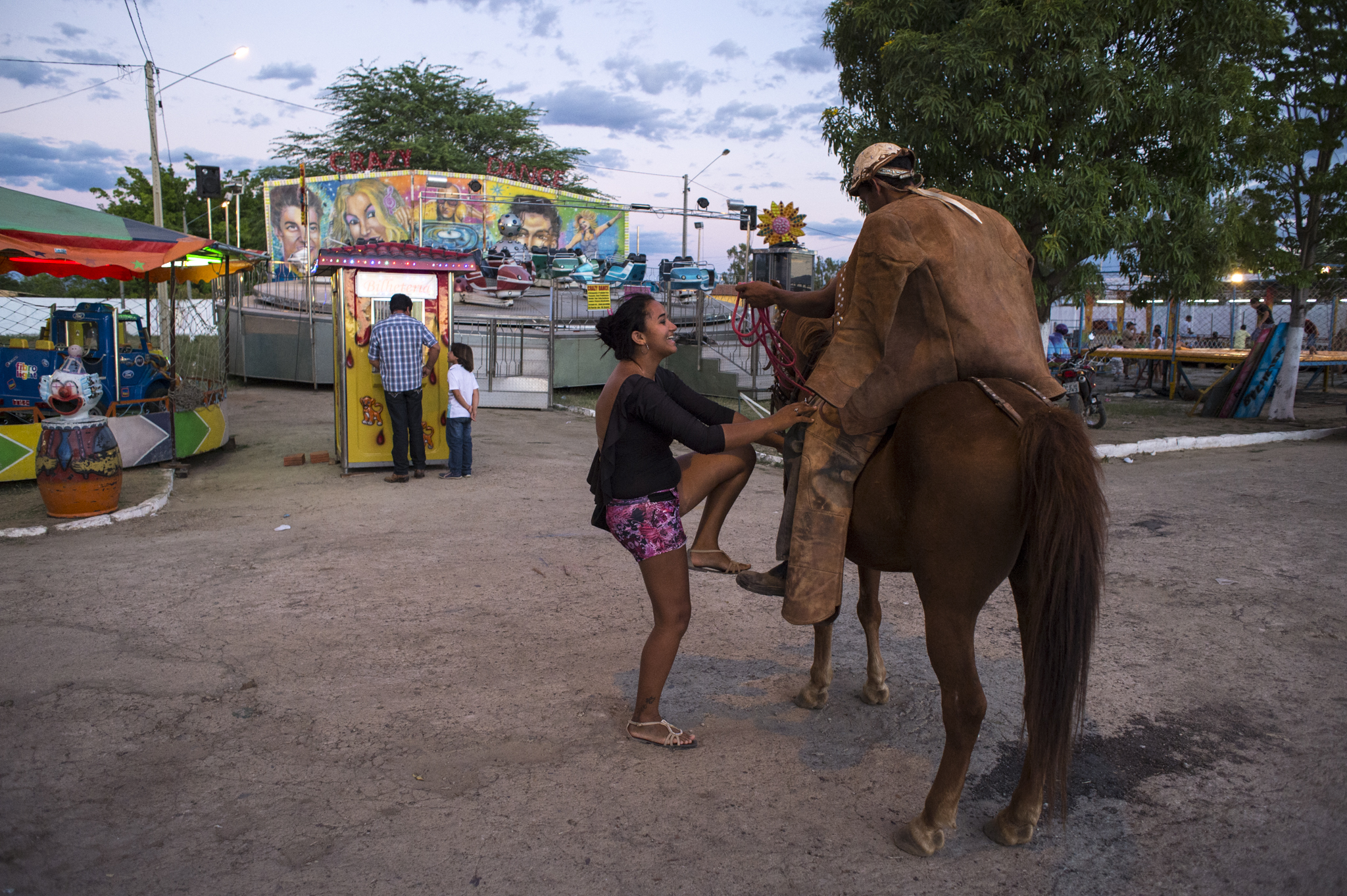  A young cowboy invites a girl to get on his horse during the Feast of São José in Custodia, Sertao Pernambucano, Brazil. 