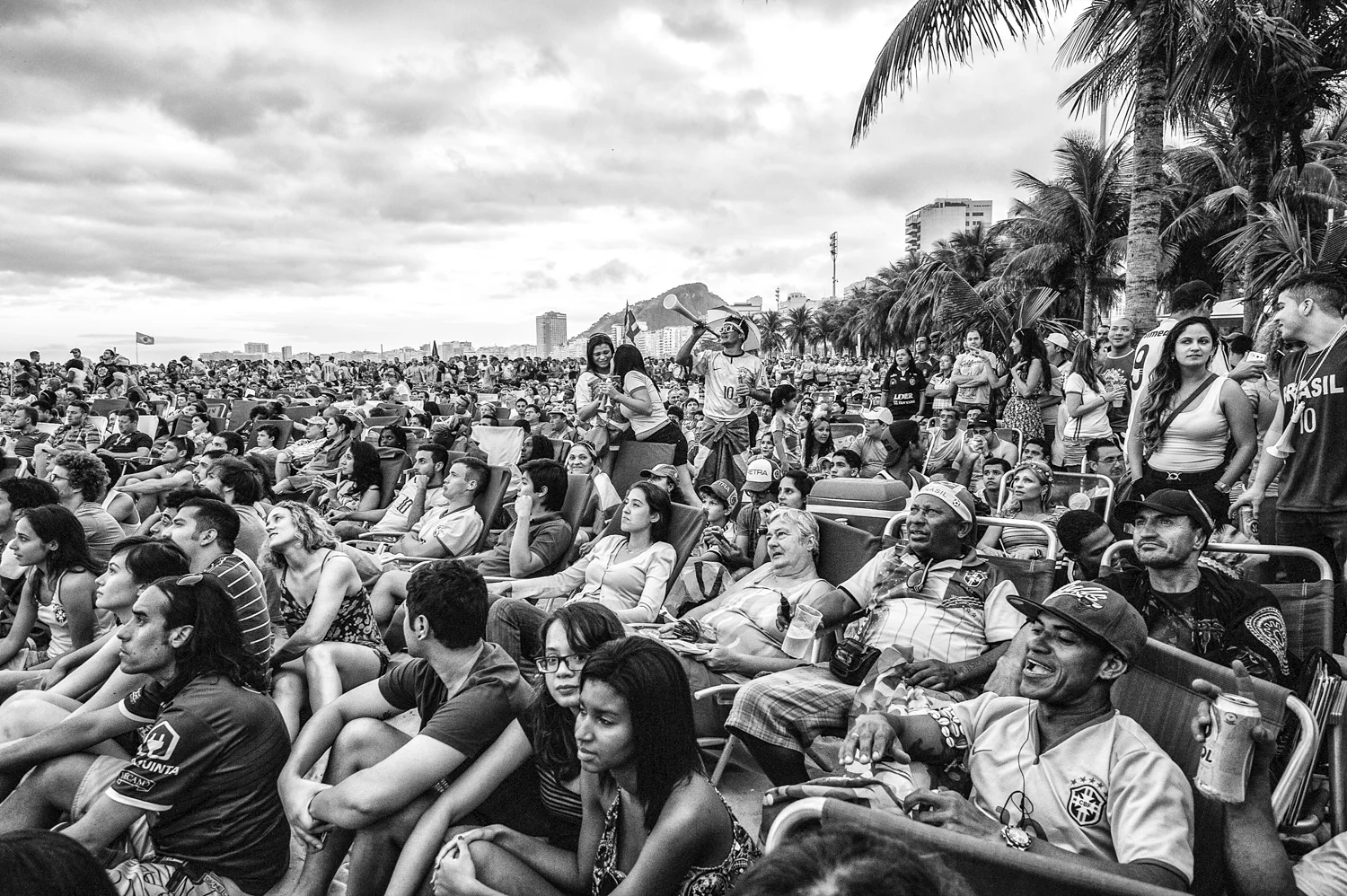  Tourists and locals are sitted together on the beach are watching the first minutes of  World Cup 2014. 