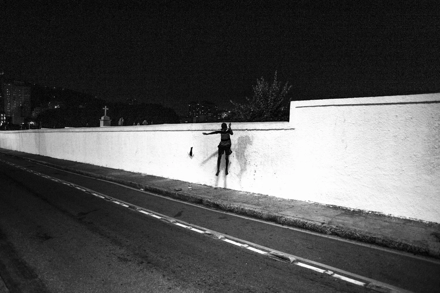  At night, a young guy with a kite jump off the Saint John the Baptist's Cemetery in Rio de Janeiro, Brazil.

Dozens of young guys from Tabajara's favela started to play kite fighting inside the adjacent cemetery since the Pacifying Police Unite( UPP