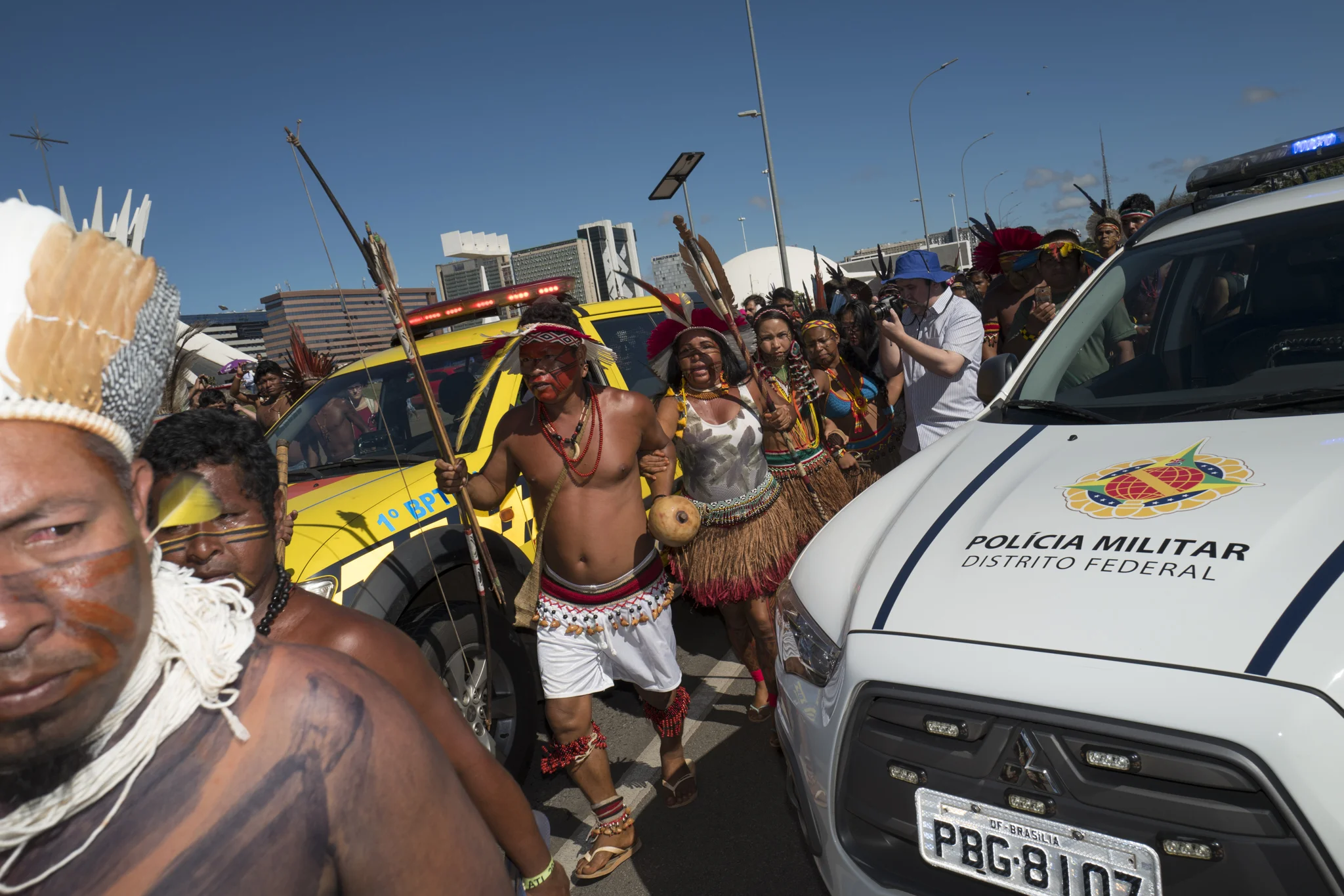  Indigenous warriors pass between the Brasilia military police cars during a protest in the direction of the Ministry of Justice 