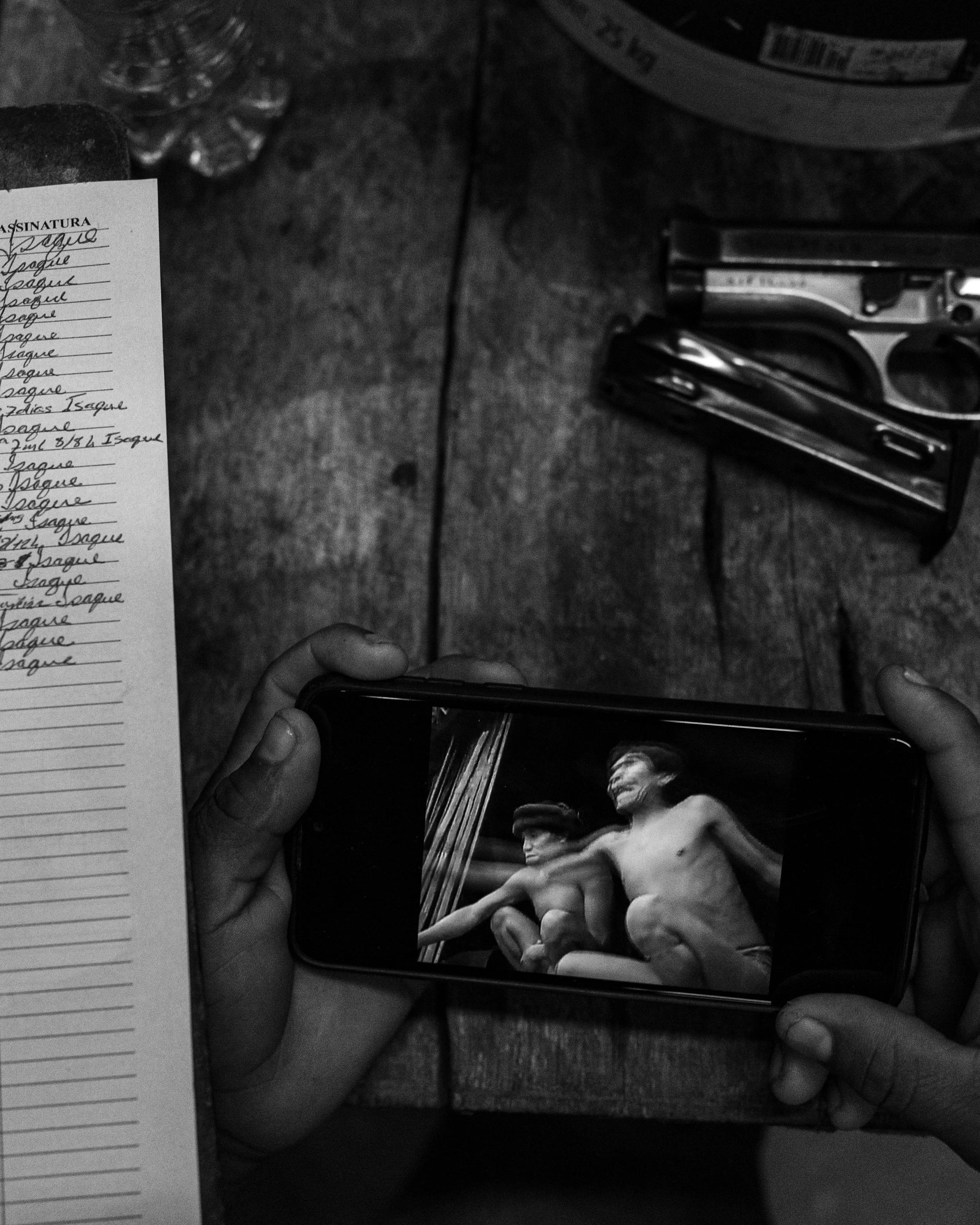 10 June, 2021  An armed Indigenous health officer watches an old documentary about Yanomami while he prepares medications for patients in Palimiu village, Brazilian Amazon.               