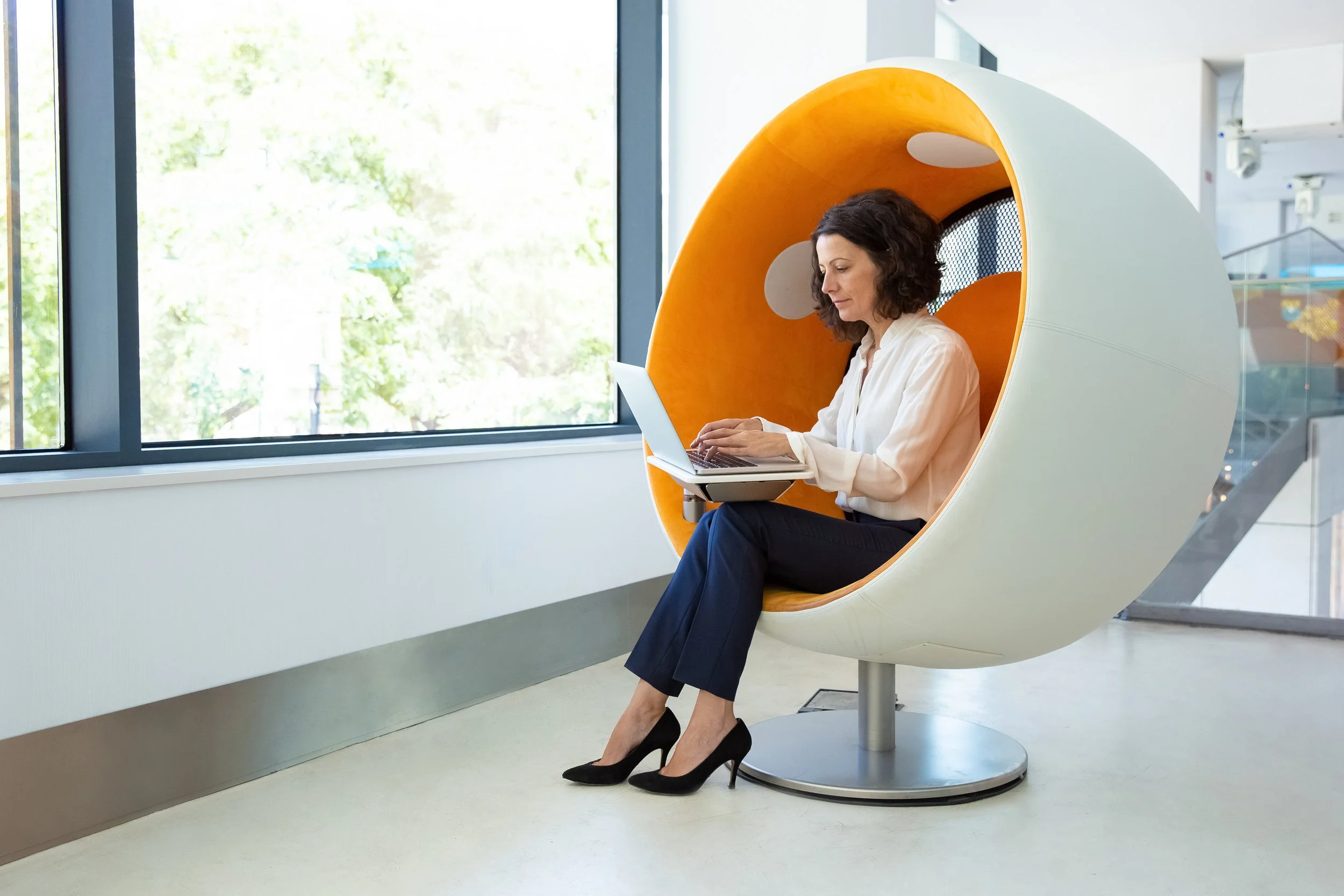 Woman working on laptop in office pod