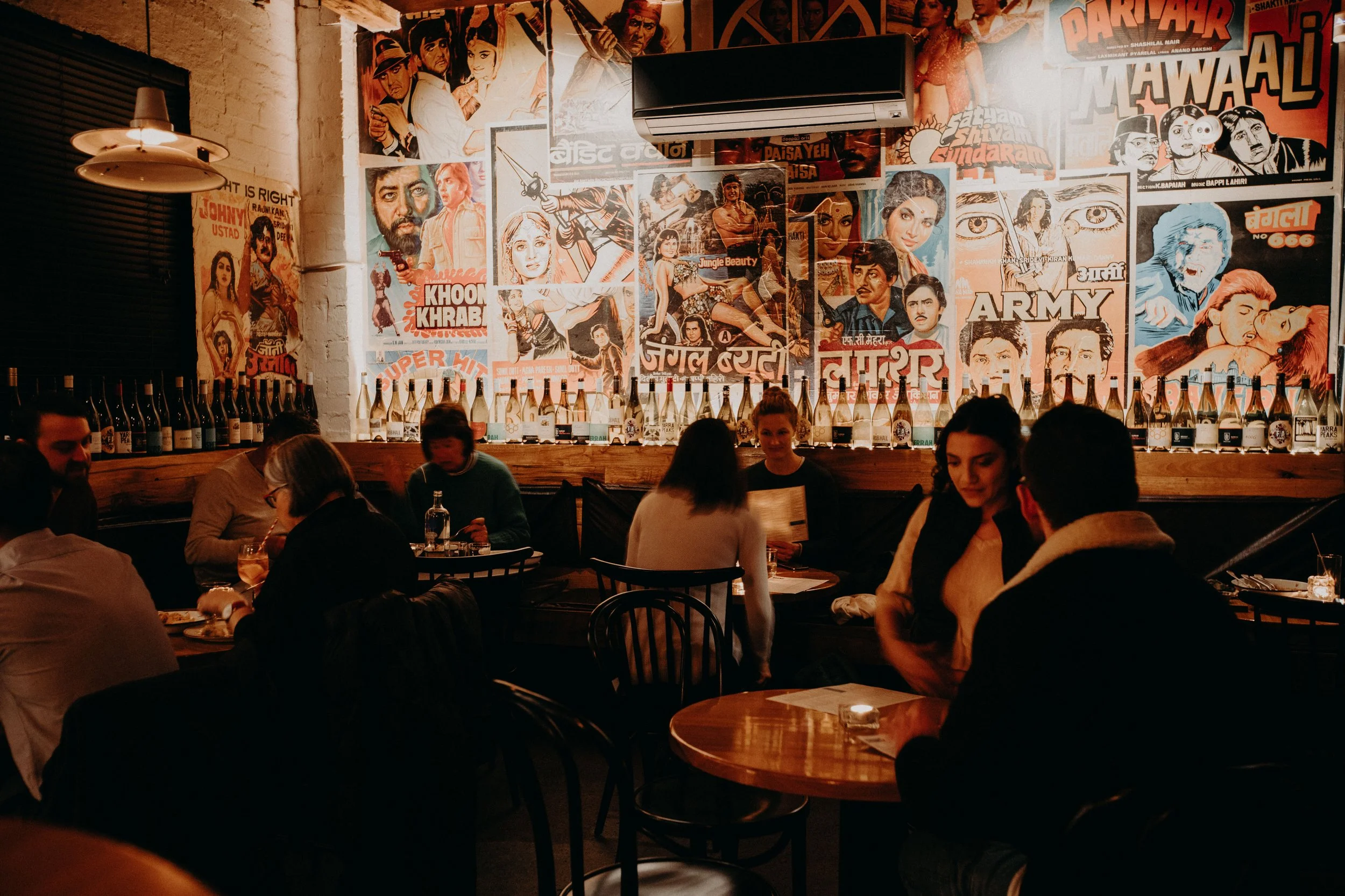 Guests dining inside Eat Drink Bhang in Brunswick, with Bollywood-style wall art, warm lighting and a relaxed evening atmosphere.