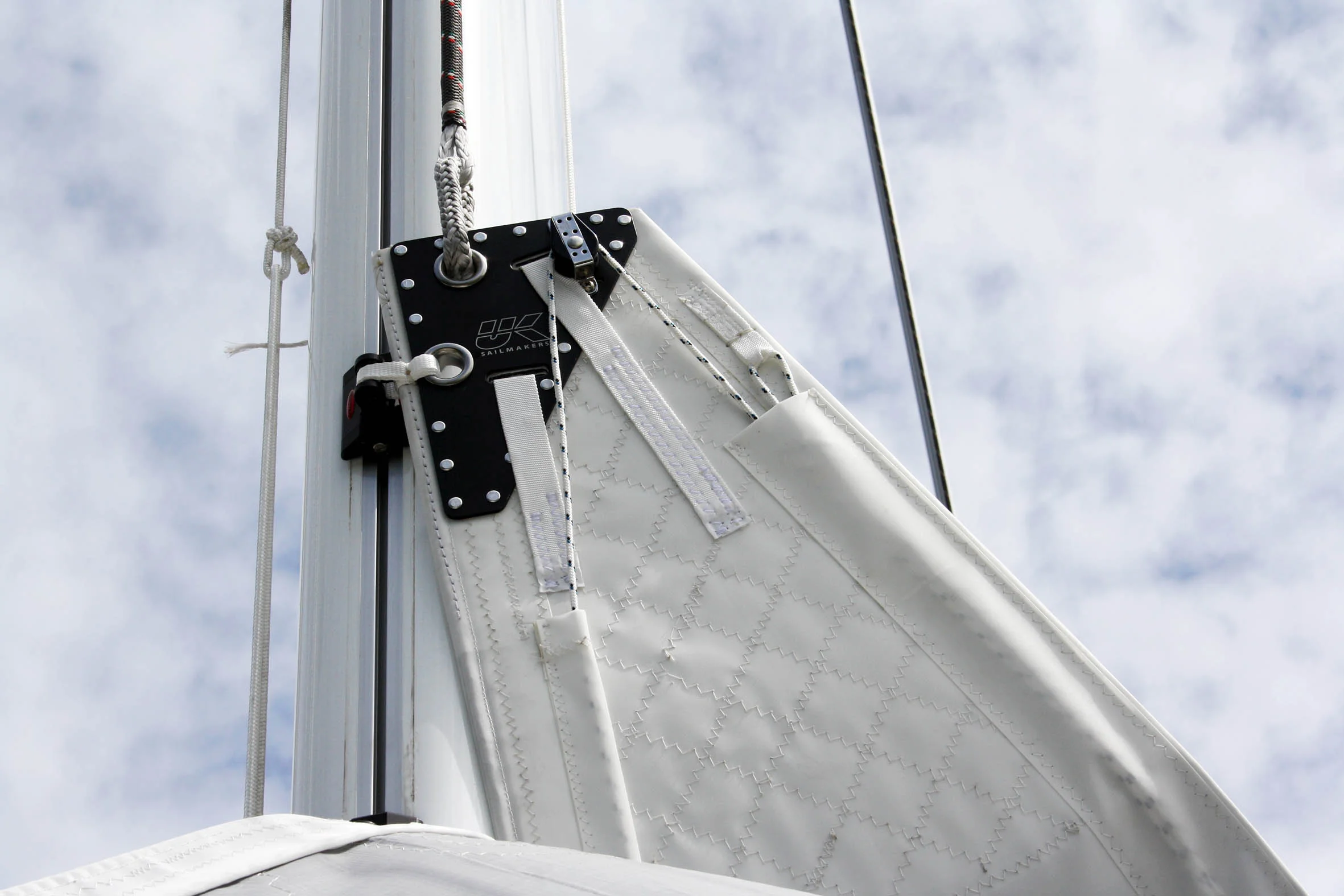 Notice the block on the back of the headboard that turns the leech line so that it comes down the luff to a cleat above the tack. An over the head leech line is needed on boats with high booms and it is the only leech line set up that can be adjusted when the back of the boom is not over the boat.