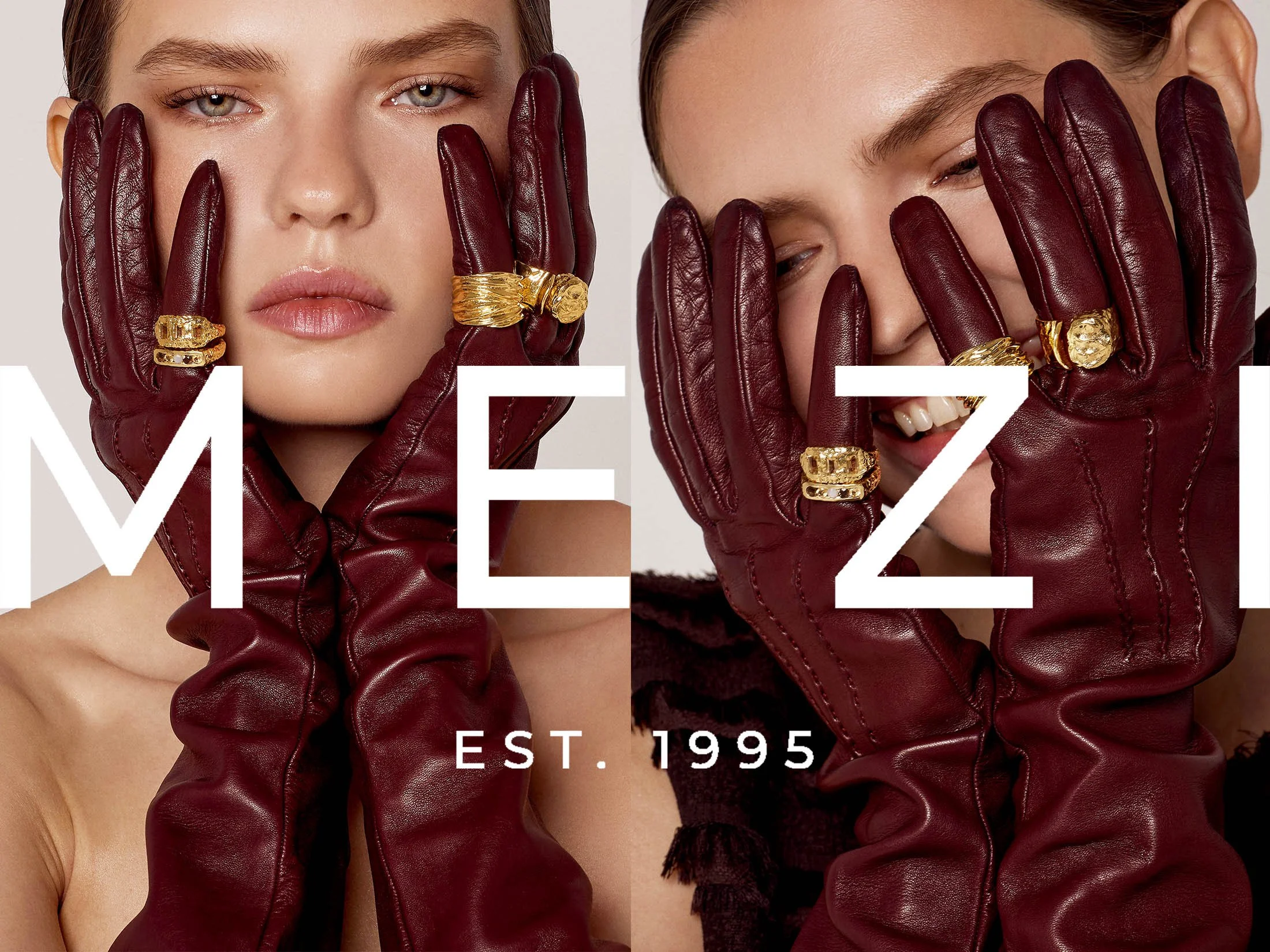 A woman with blue eyes and light skin wearing burgundy leather gloves with gold rings, covering parts of her face and smiling.