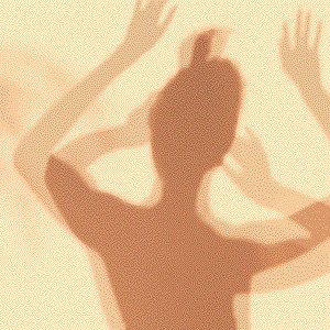 Shadow of a person with multiple raised hands on a beige wall.