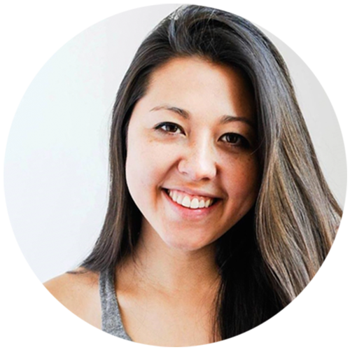 Close-up of a young woman with long brown hair smiling, wearing a gray tank top, with a white background.