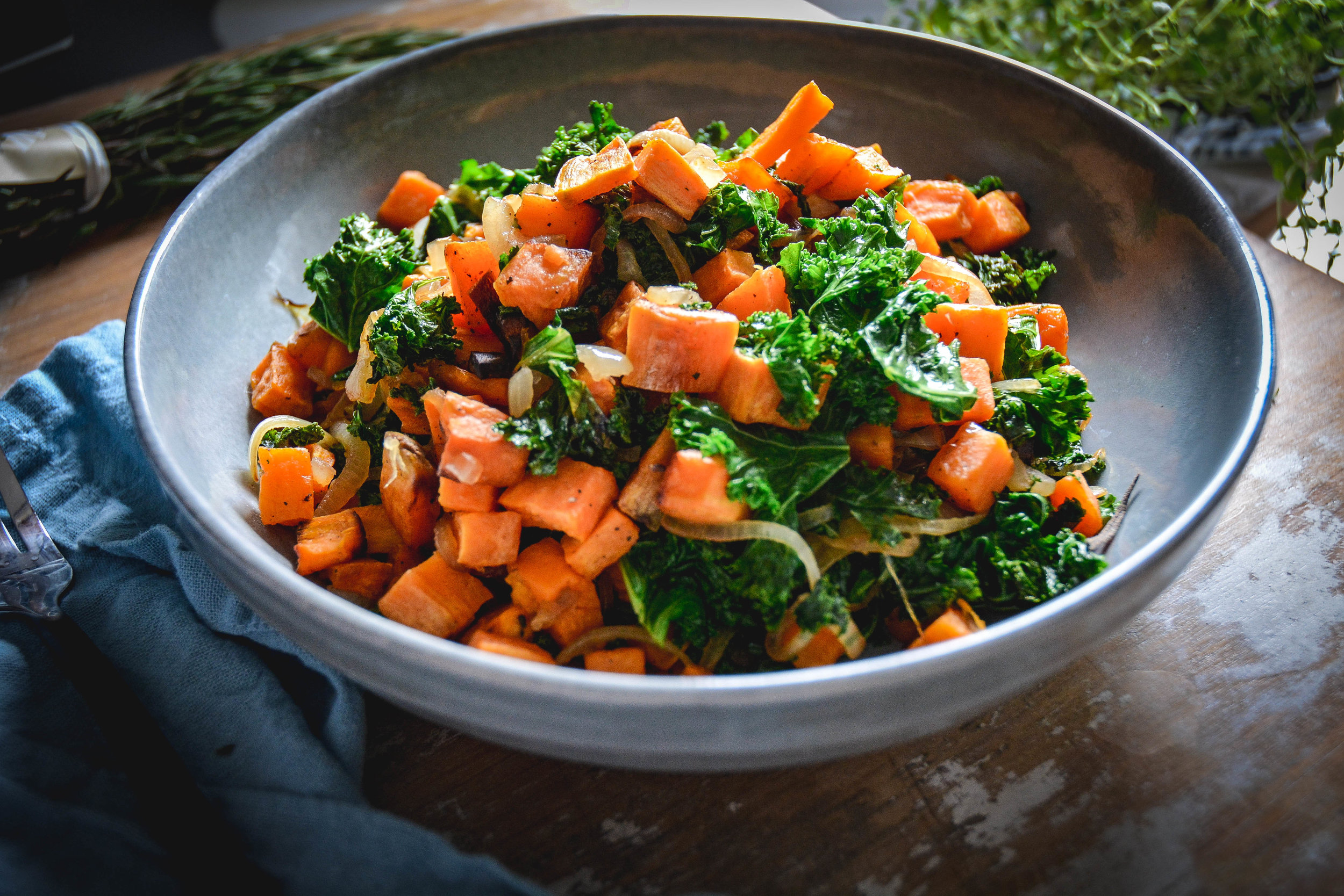 sweet potatoes with kale in bowl, on table with blue napkin