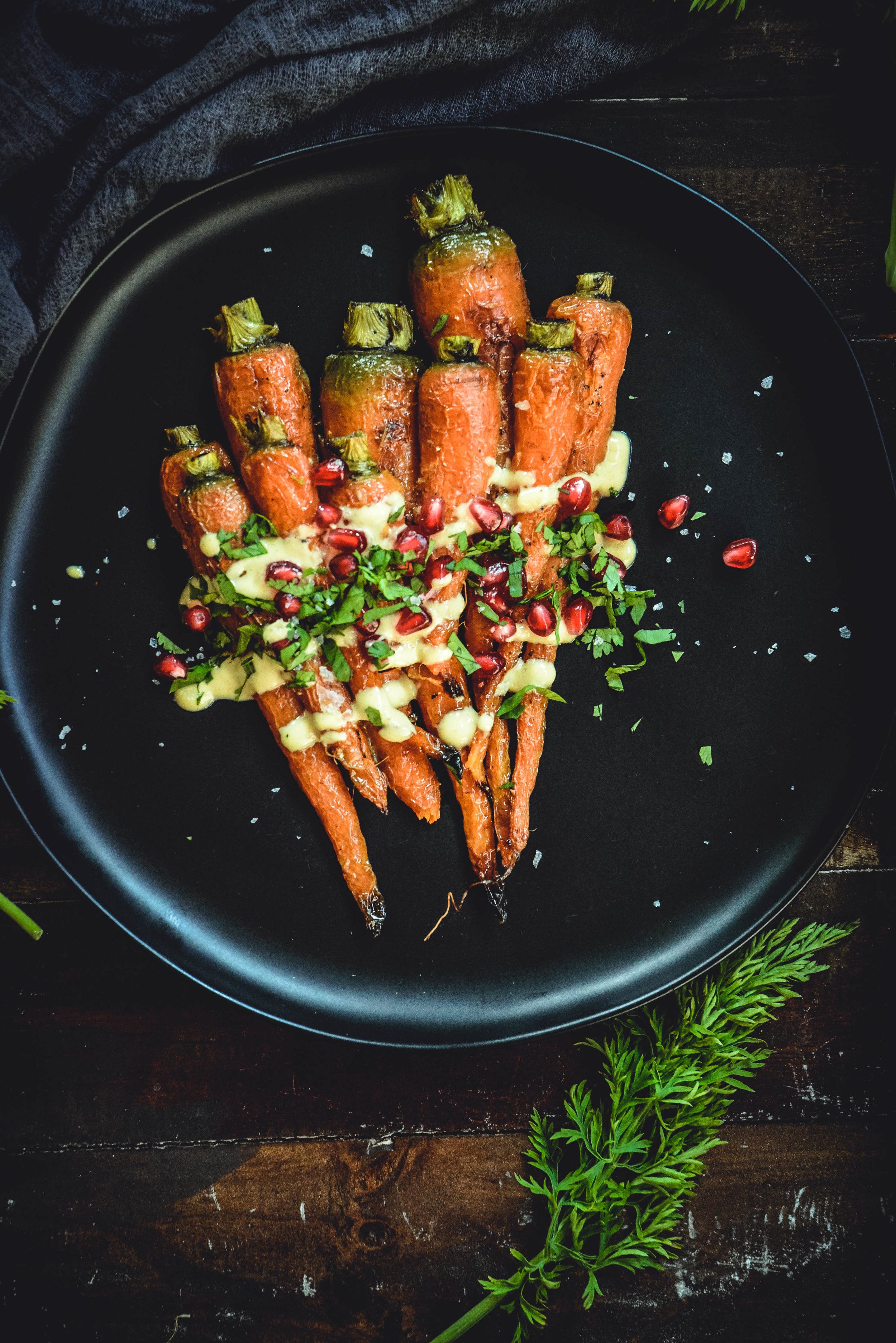 Roasted Carrots With A Simple Orange Tahini Sauce And Pomegranate on black plate