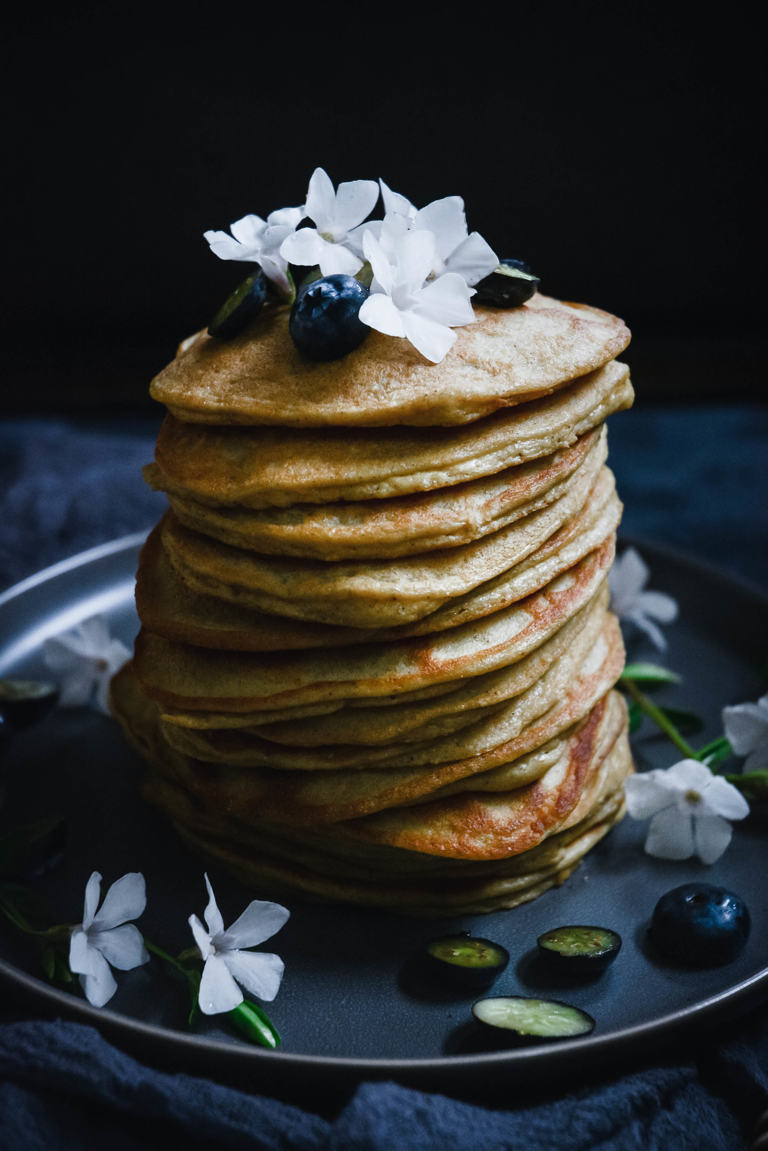 pancakes stacked and topped with flowers and blueberries