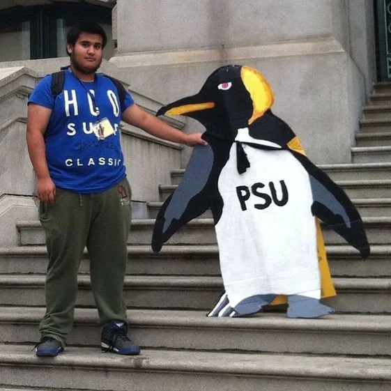 A young male Providence high school student holds the PSU penguin proudly.