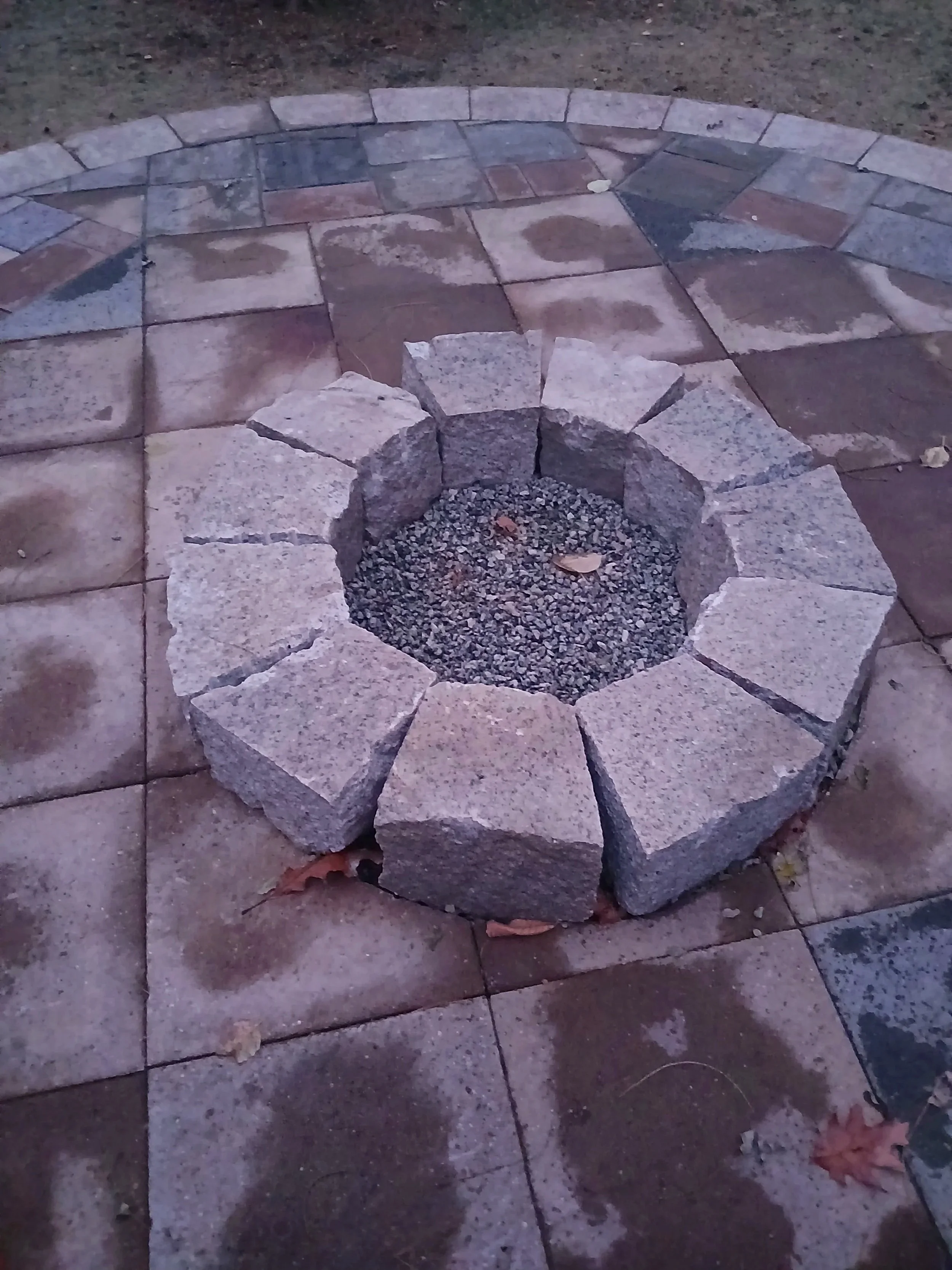 Hand split granite fire pit inlaid within paver sitting patio