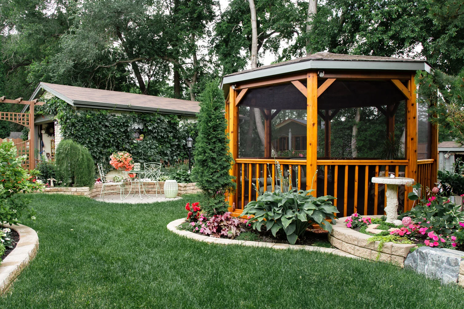 A wide view of a multi-level backyard retreat in Winnipeg featuring winding Barkman stack stone terraced walls and a central gazebo. Expertly integrated landscaping creates a private and functional garden space.