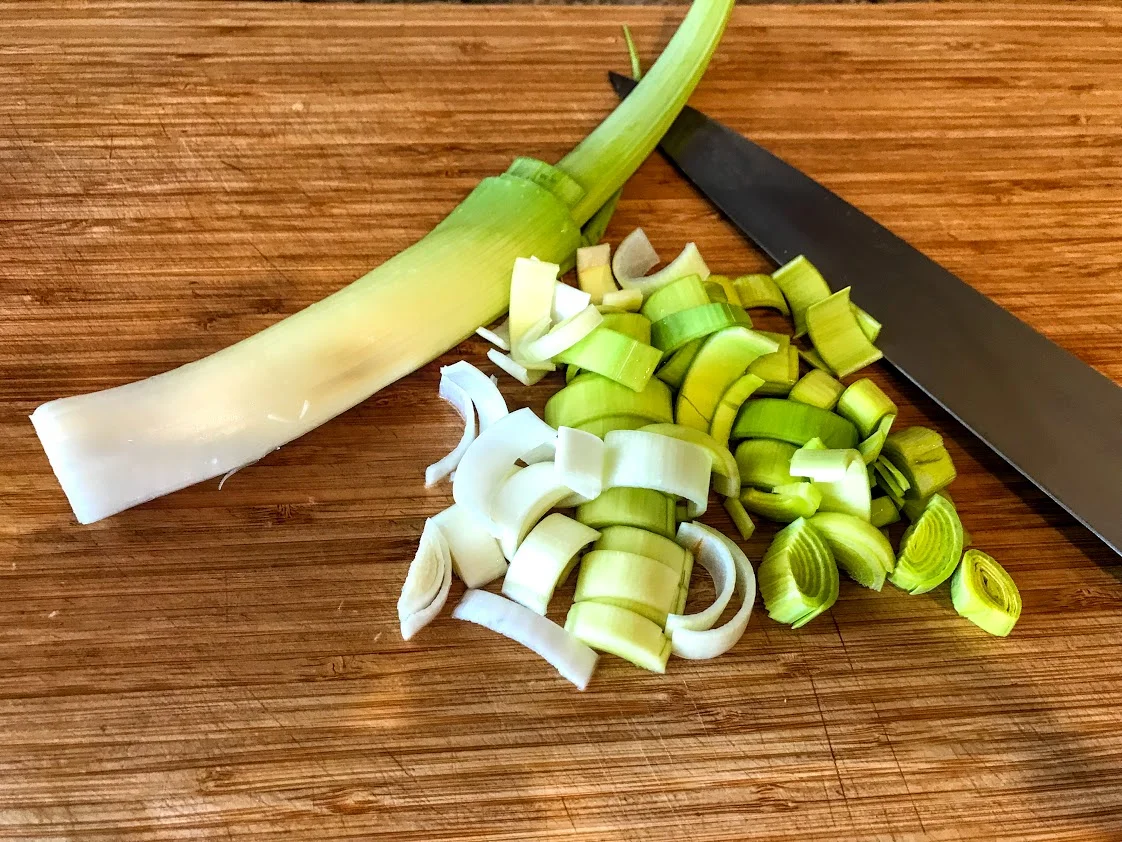 Slice only the pale green and white parts, discarding the root and deep green parts.