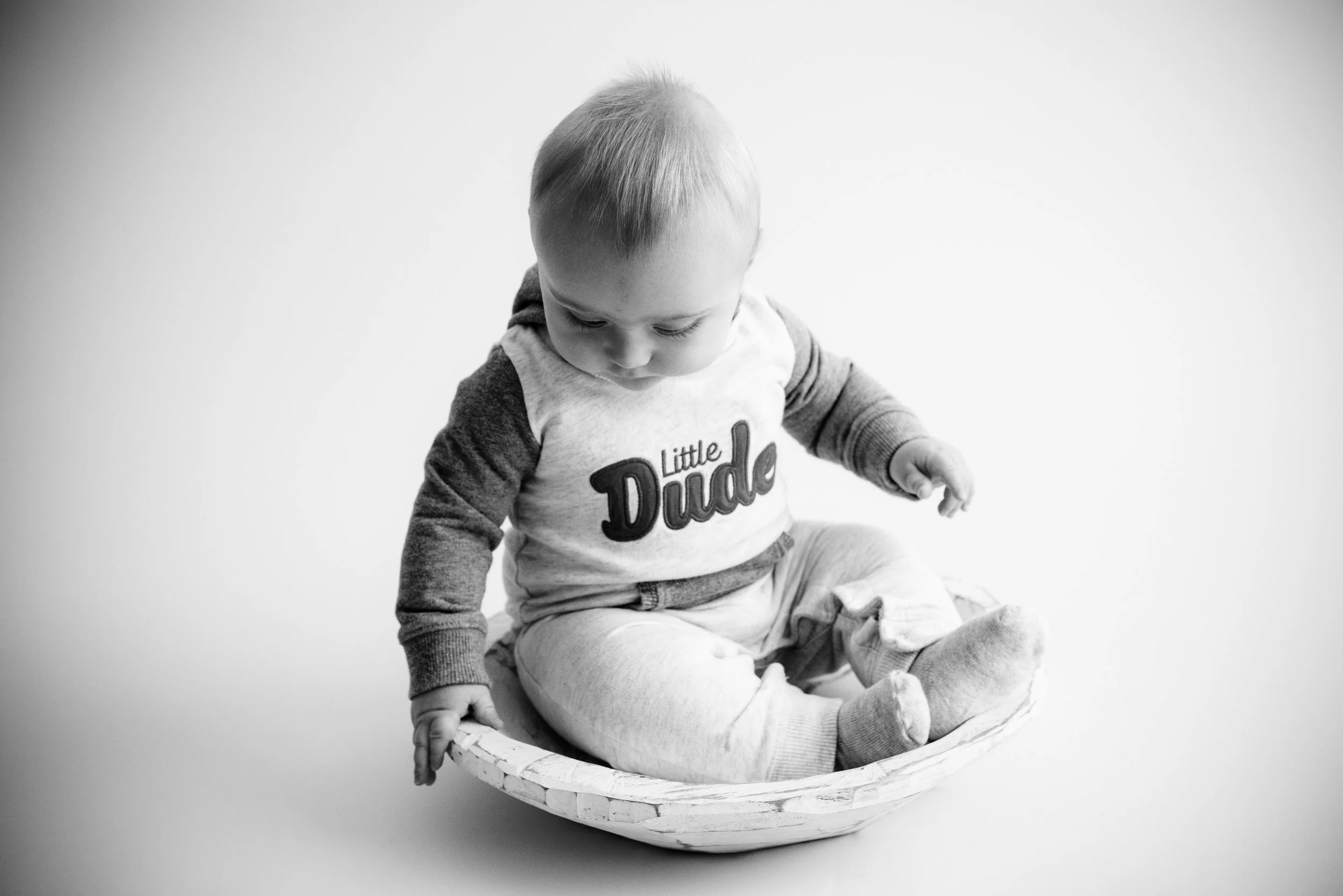 Black and white photo of a six month old baby boy sitting up on own in a bowl in Iowa. 