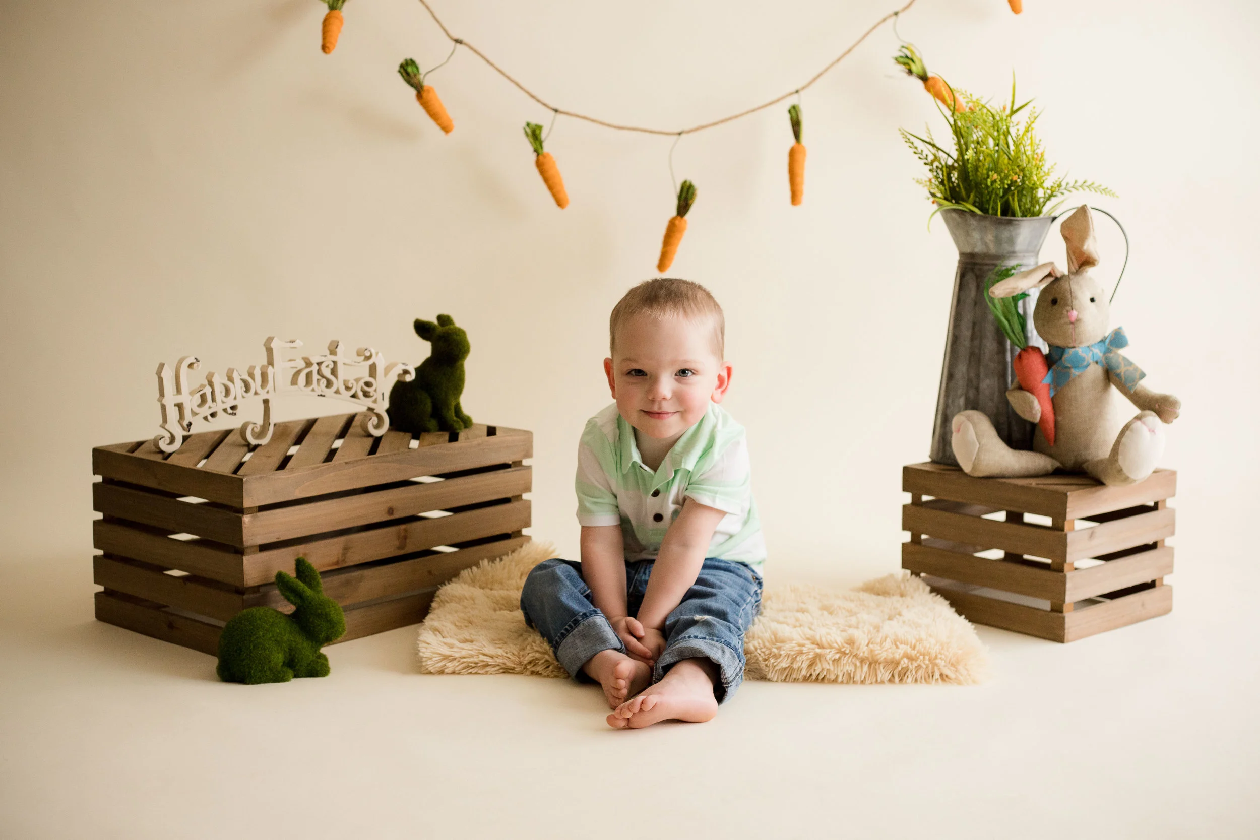 Two year old boy sitting and smiling at camera during indoor photo session. 